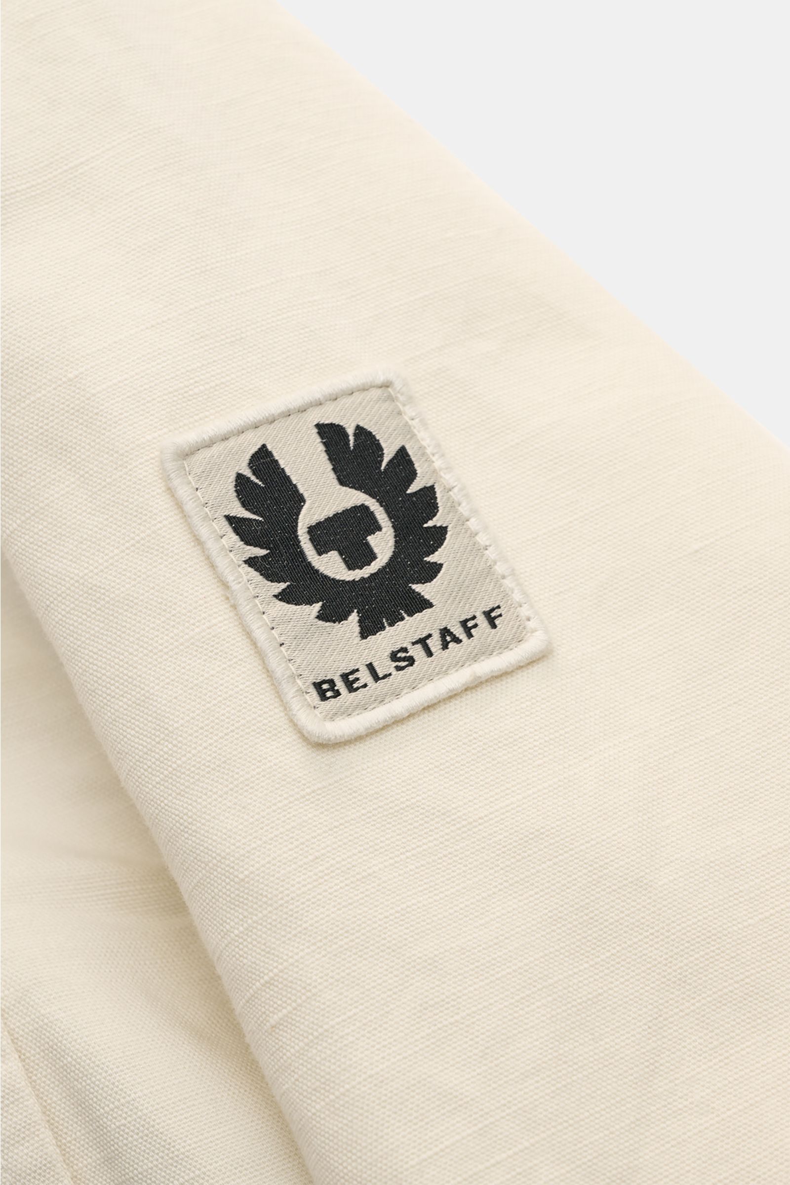 Belstaff Overshirt 'Maritime' sand close-up of sleeve with woven logo label, showing cotton-linen fabric texture from a side angle.