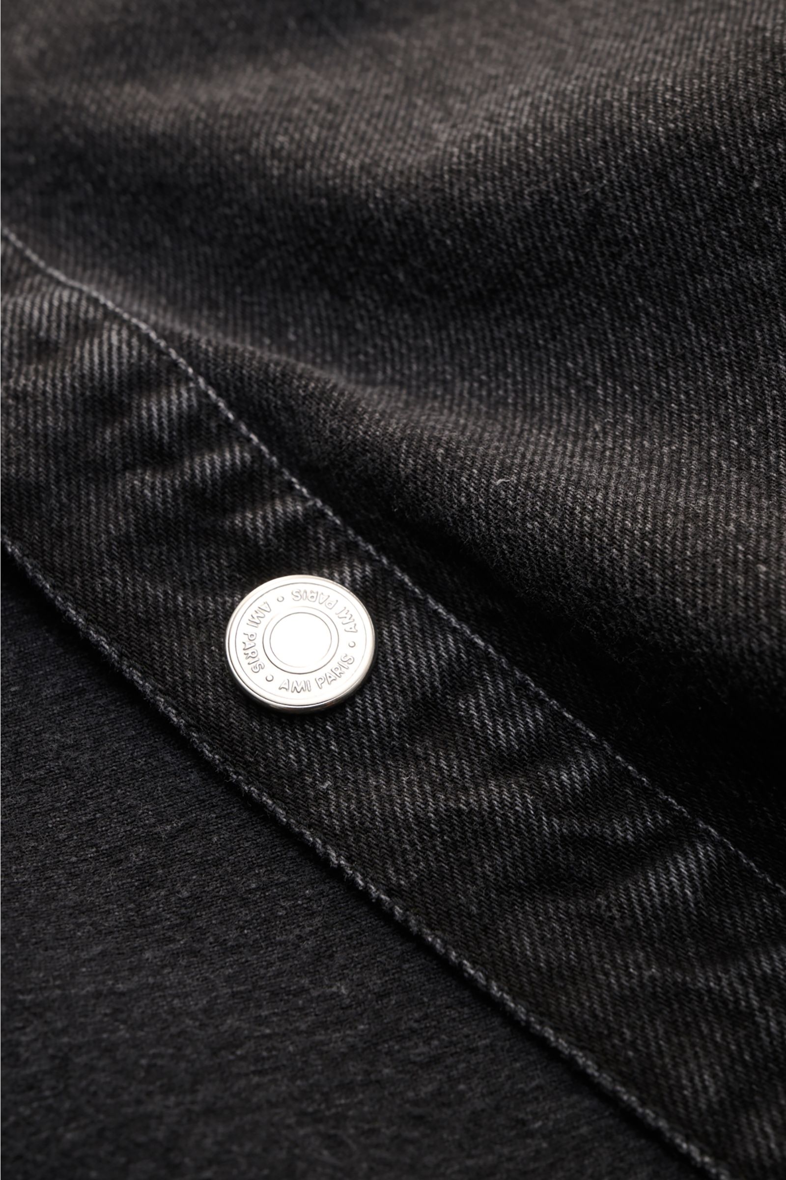 Nahaufnahme des Ami Paris Jeans-Overshirts dunkelgrau aus Baumwoll-Denim mit Logo-Knopfleiste und typischer Oversize-Haptik, frontal fotografiert.