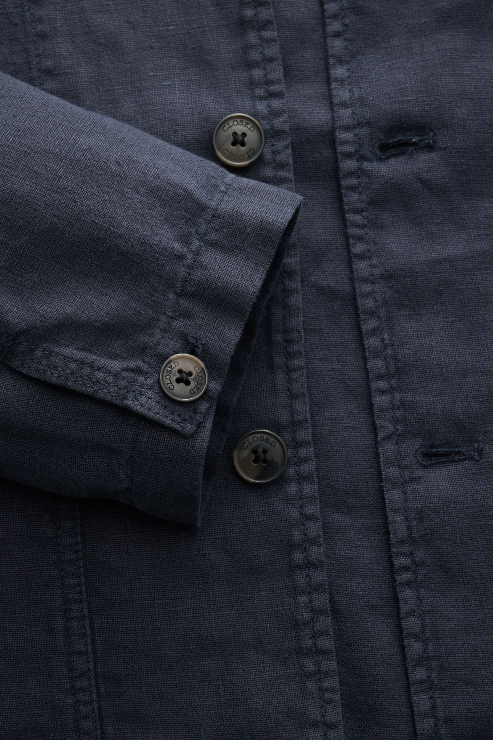 Nahaufnahme des Closed Overshirt 'Cargo Jacket' navy aus reinem Leinen mit kastiger Silhouette, Knopfleiste und Ärmelabschlüssen, fotografiert von schräg oben.