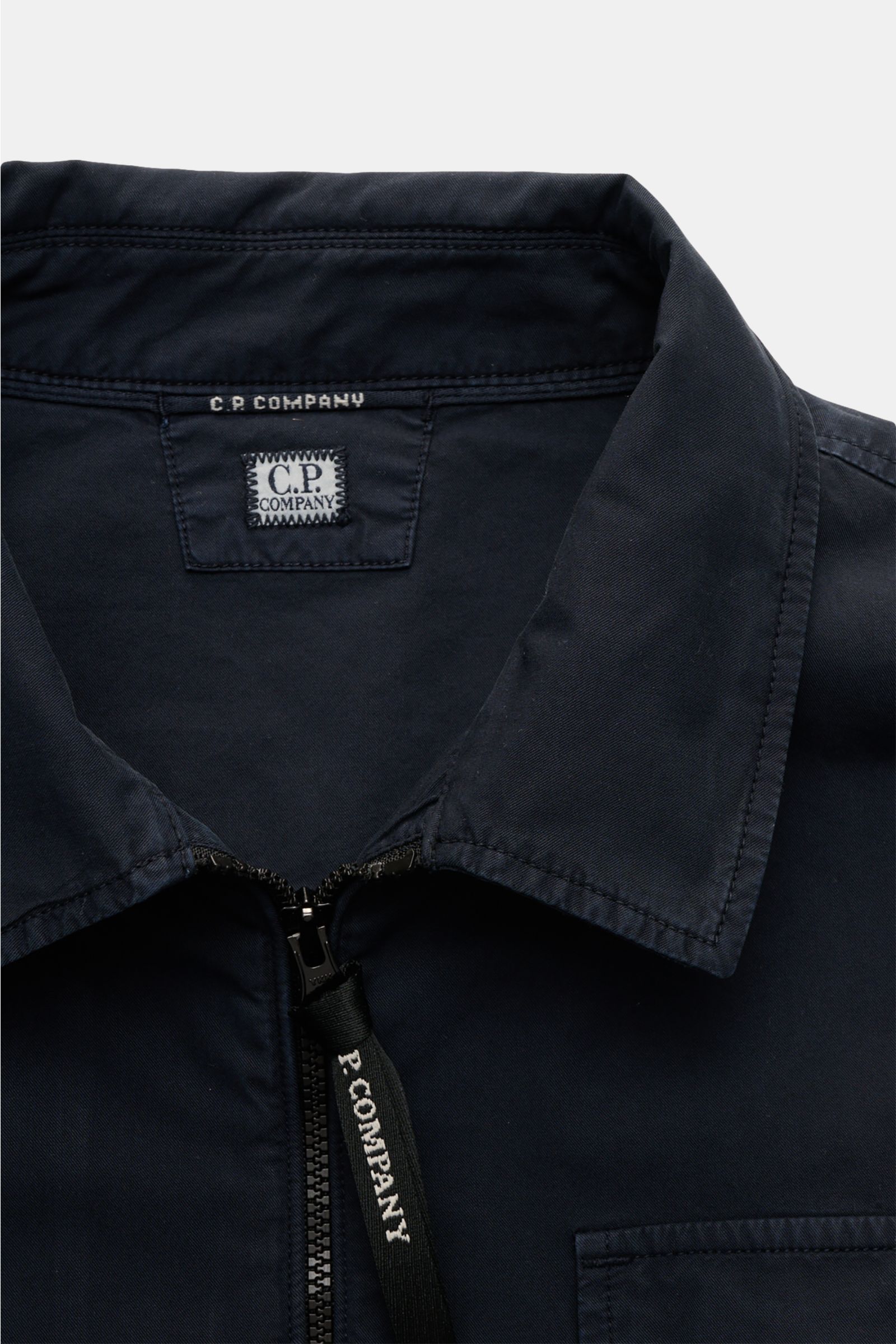 Close-up front view of the C.P. Company Overshirt navy, made of pure cotton, slim fit with two-way zipper, collar, chest pocket, logo sleeve pocket, and cuffed sleeves. Lässiges Layering-Piece: Das Overshirt von C.P. COMPANY ist der ideale Begleiter für u