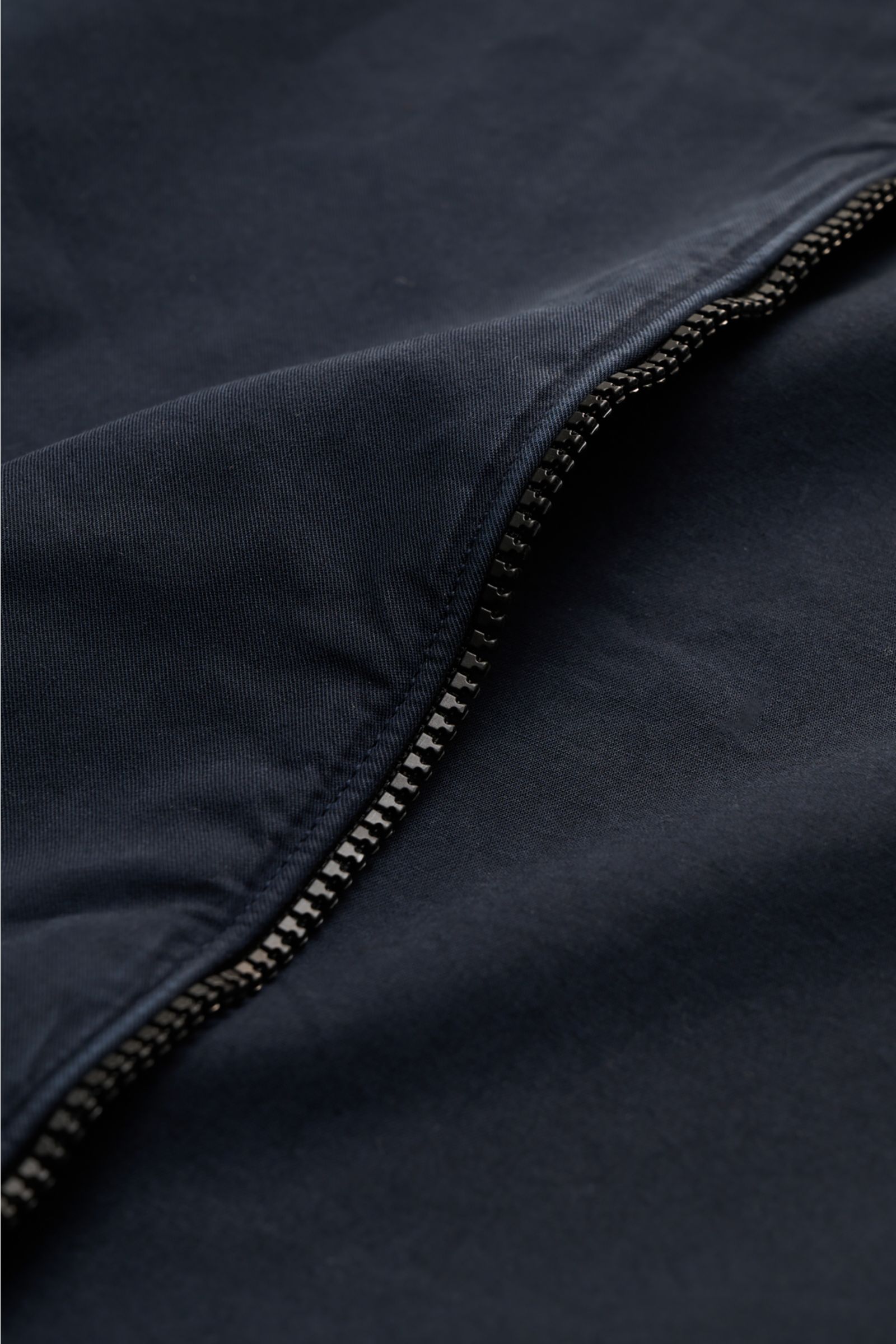 Close-up, angled view of the zipper and upper fabric of the C.P. Company Overshirt navy, made of pure cotton with a two-way zipper, slim fit, chest pocket with flap, logo detail on sleeve pocket, cuffed sleeves, and a fold-down collar, ideal for casual sp