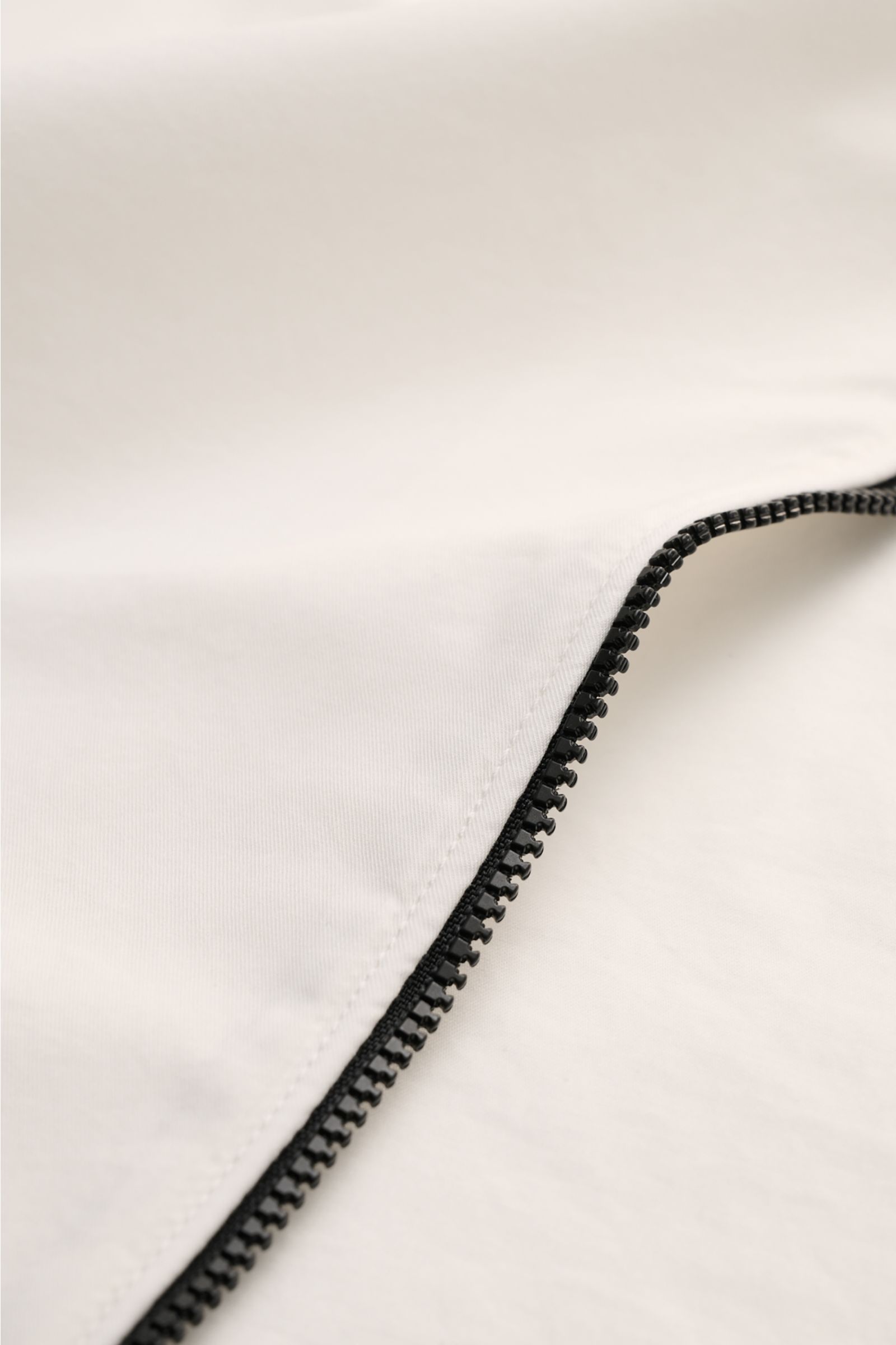 C.P. Company Overshirt offwhite close-up from above showing the black two-way zipper on lightweight pure cotton fabric, slim fit design.