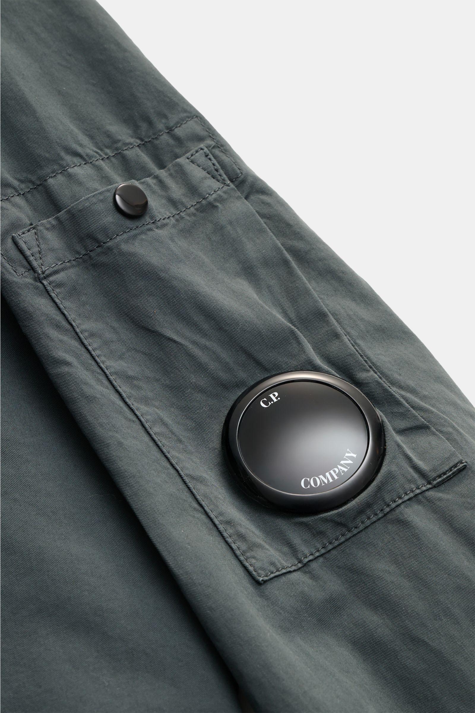 Close-up front view of the C.P. Company Overshirt dunkelgrau showing the sleeve pocket with logo detail, made of pure cotton, slim fit, lightweight quality, two-way zipper, collar, chest pocket with flap, and cuffed sleeves, ideal for casual urban spring 