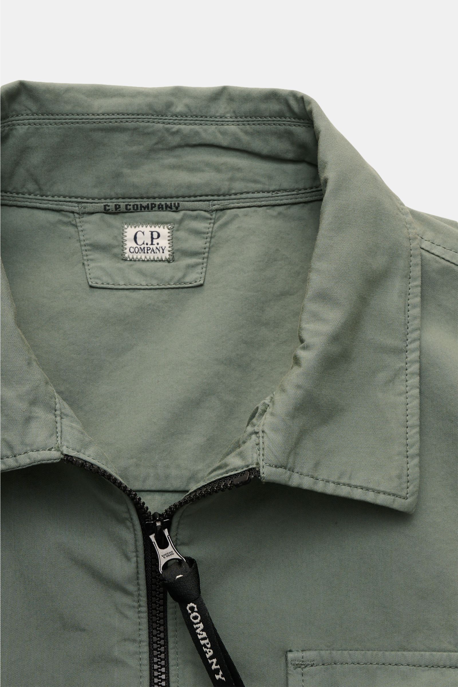 C.P. Company Overshirt salbei shown from the front detail view, featuring a collar, two-way zipper, and cotton fabric. Lässiges Layering-Piece: Das Overshirt von C.P. COMPANY ist der ideale Begleiter für urbane Frühlingslooks. Reine Baumwolle, leichte Qua