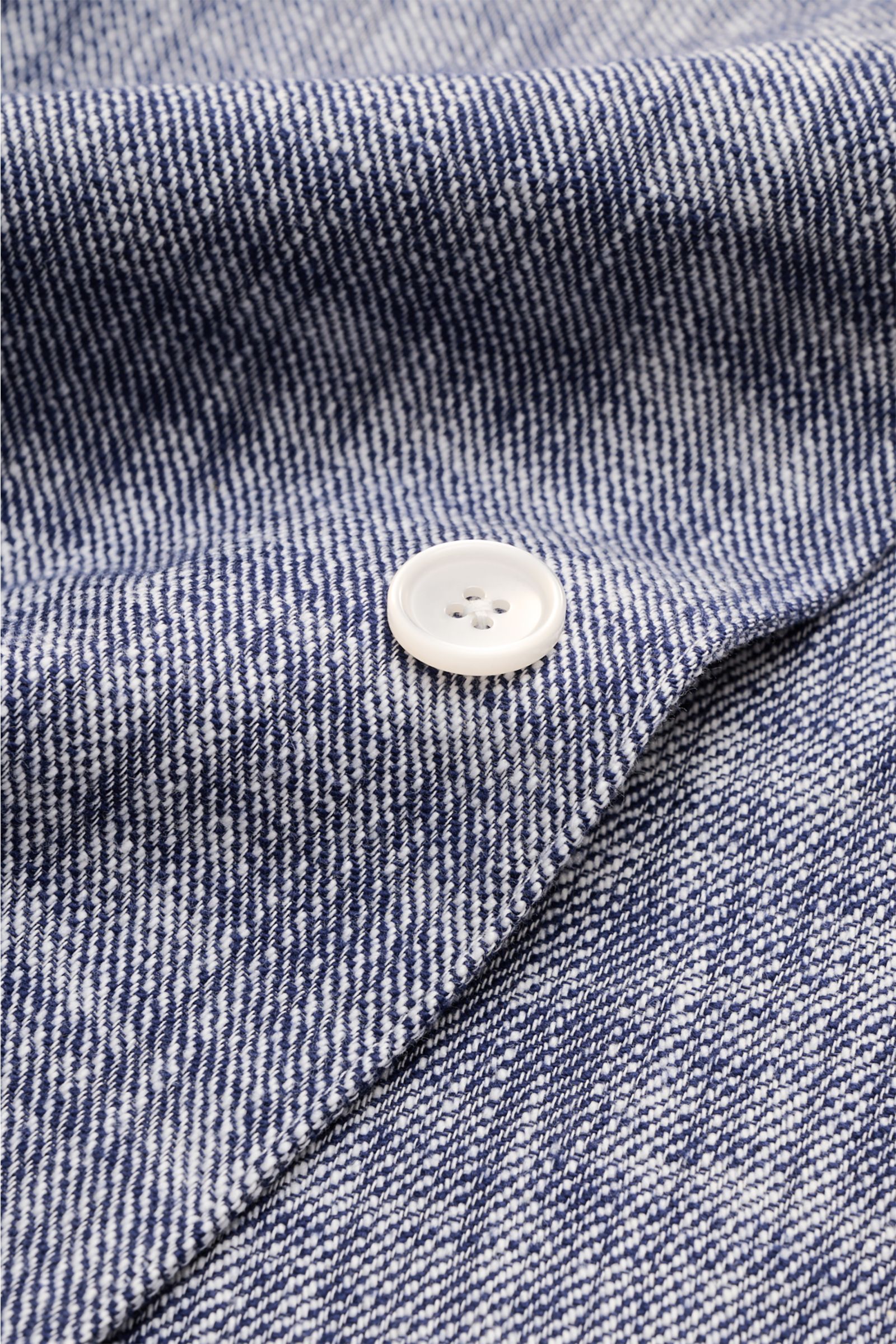 Close-up view of the Officine Générale Overshirt 'Sheldon' navy/weiß showing white button on textured slub-cotton fabric. Authentisch im Ausdruck und modern in der Silhouette, verbindet das Overshirt 'Sheldon' von OFFICINE GÉNÉRALE zeitgemäße Lässigkei