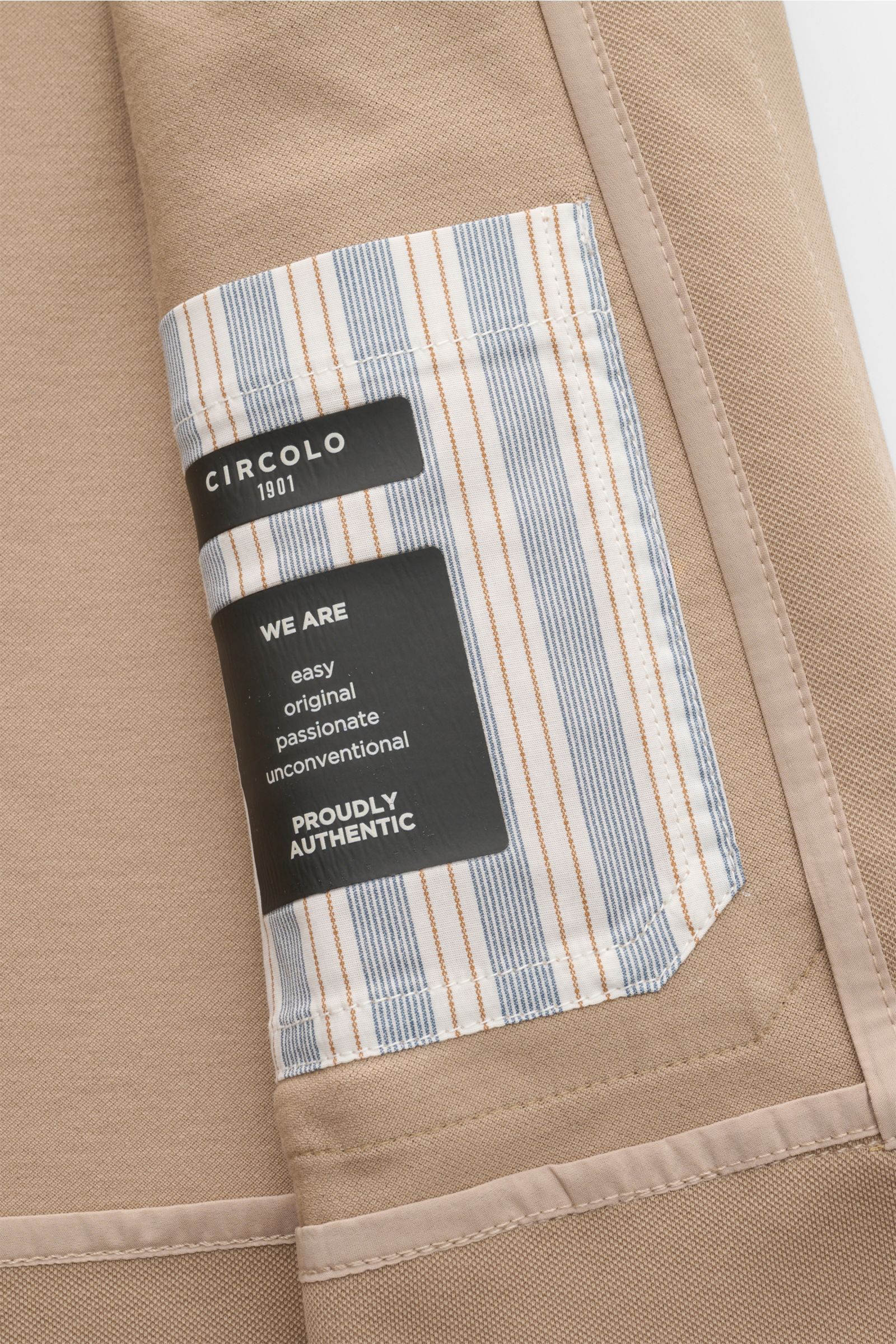 Nahaufnahme des Innenbereichs eines Circolo 1901 Overshirt sand mit gestreifter Innentasche und Markenlabel, Detailansicht.
