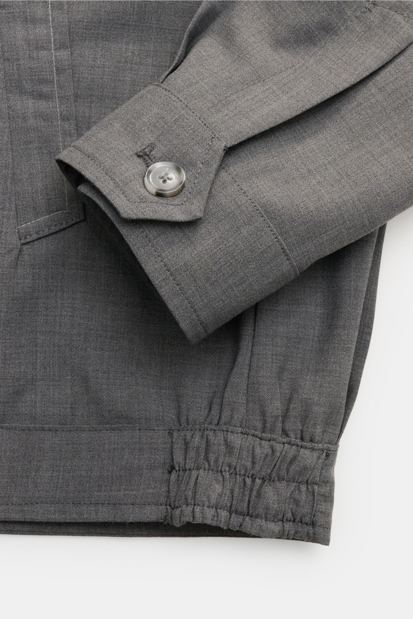 Close-up of the sleeve and bottom hem of the Briglia 1949 Overshirt 'Bill' dunkelgrau meliert, showing buttoned cuff and elastic waist, photographed from above.

Italienisches Flair in Ihrer Garderobe erhalten Sie mit dem smarten Overshirt 'Bill' aus d