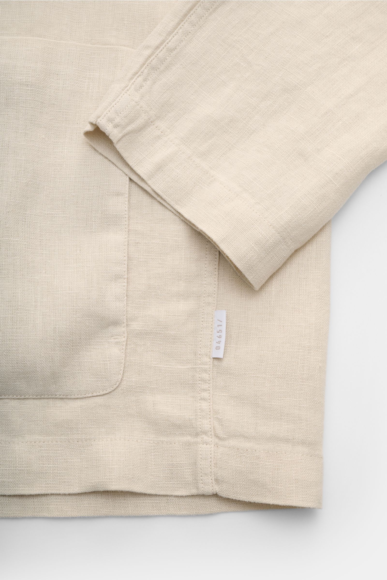 Detailaufnahme des 04651/ A trip in a bag Overshirt 'Linen Jacket' beige aus reiner Leinenqualität, weicher Griff, Slim Fit, mit Ärmel und aufgesetzter Fronttasche, fotografiert von oben.