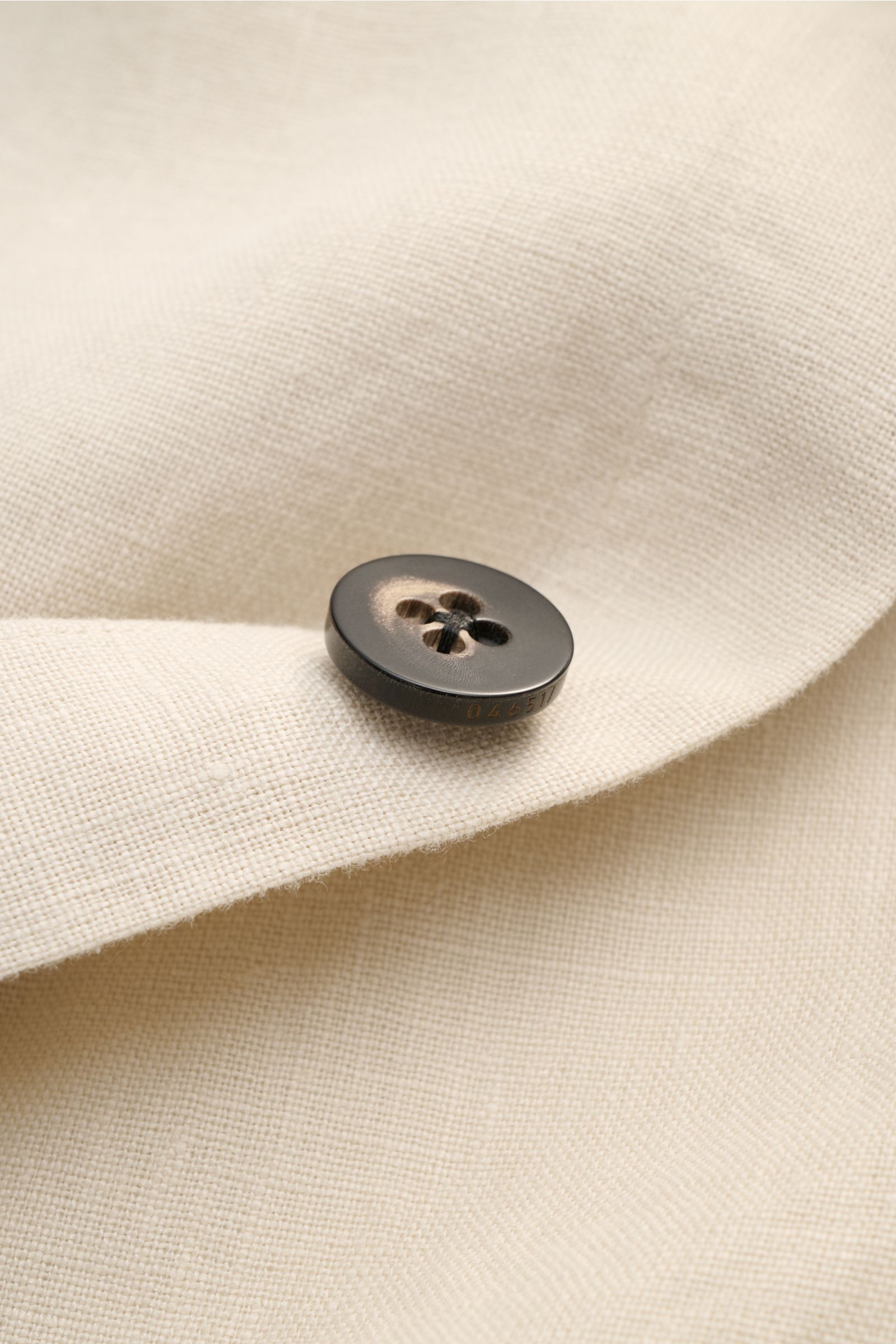 Beige Leinenstoff mit Knopf in Nahaufnahme, Detail des 04651/ A trip in a bag Overshirt 'Linen Jacket' Slim Fit mit weichem Griff.