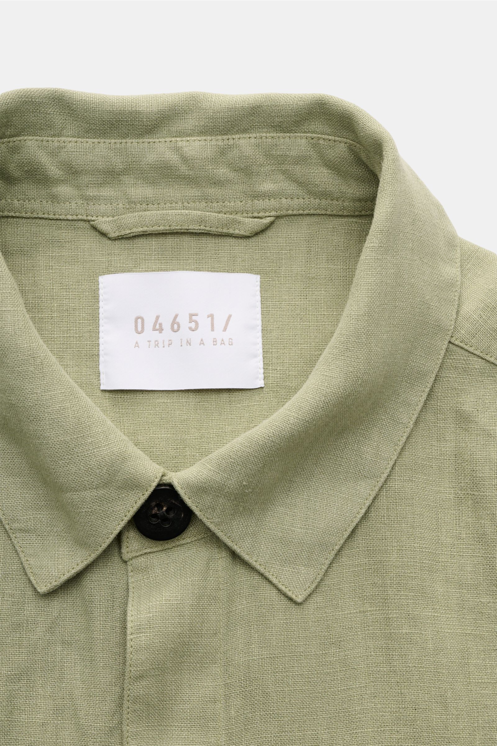Nahaufnahme von Umlegekragen und Knopf des 04651/ A trip in a bag Overshirt 'Linen Jacket' salbei aus weichem, reinem Leinen, Slim Fit.