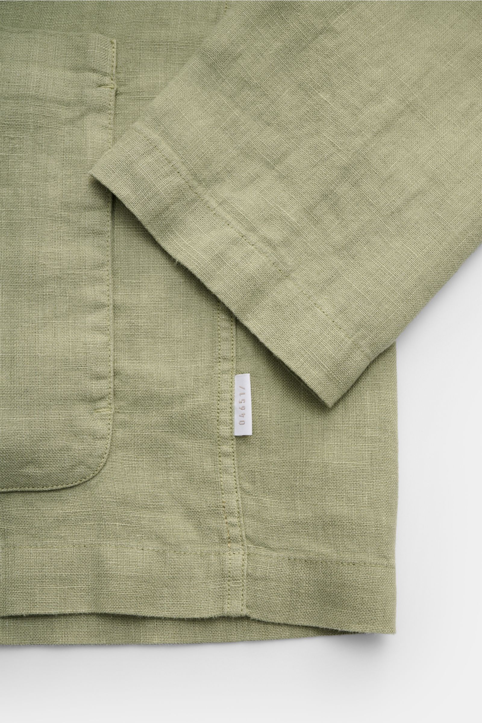 Nahaufnahme des salbeigrünen 04651/ A trip in a bag Overshirt 'Linen Jacket' aus reinem Leinen mit weichem Griff, Slim Fit, Umlegekragen und aufgesetzter Fronttasche, fotografiert von oben.