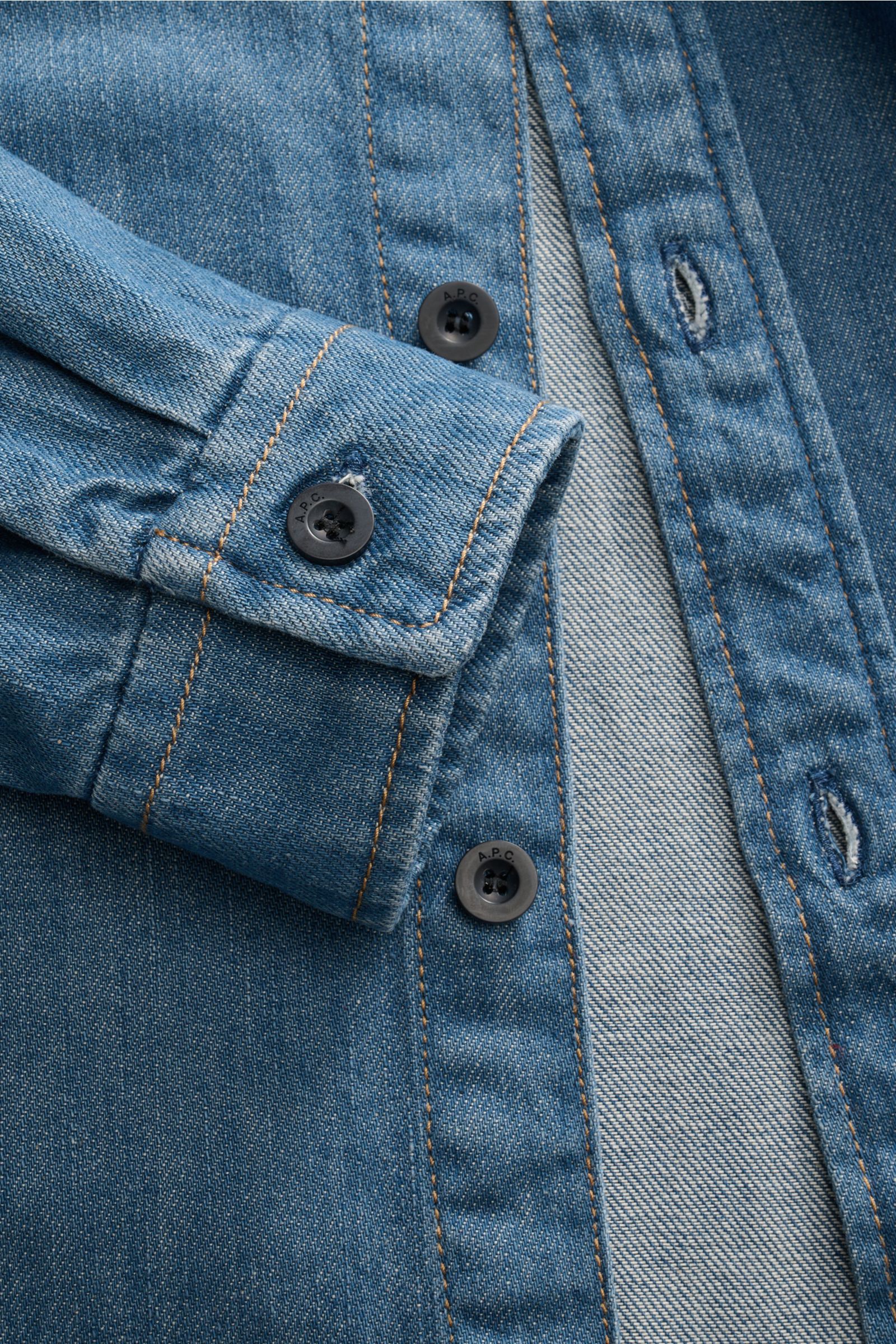 Nahaufnahme des A.P.C. Jeans-Overshirts rauchblau von schräg oben, zeigt Kent-Kragen, Slim Fit, Knopfleiste und Sportmanschette aus reiner Baumwolle Denim.