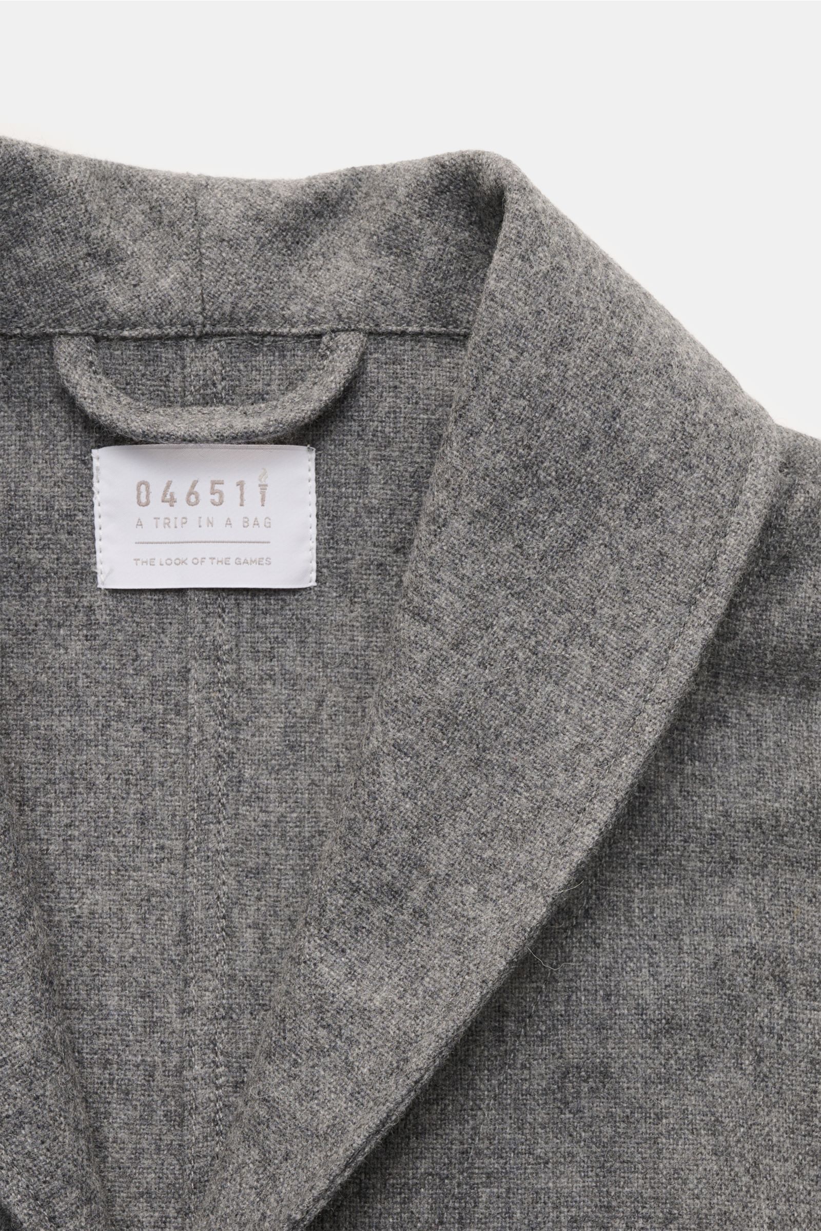 Close-up front view of the 04651/ A trip in a bag Overshirt dunkelgrau meliert showing soft wool blend fabric, shawl collar, and label inside collar. Stilvoll durch die Übergangszeit: Das Overshirt aus der 'Look of the Games' Capsule von 04651/ A TRIP IN 