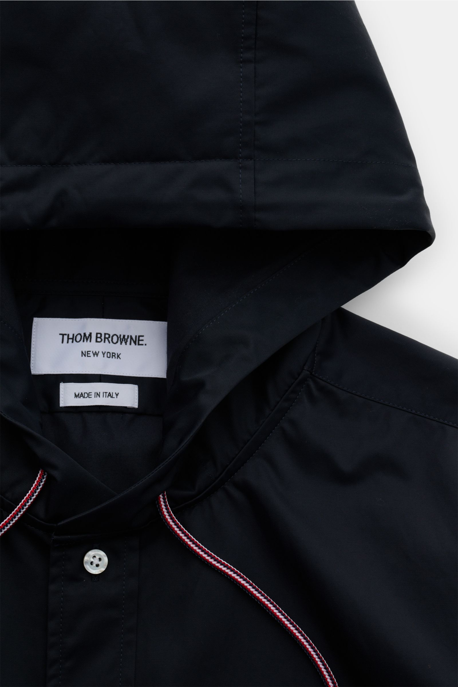 Close-up front view of the black Thom Browne Overshirt - F1066 with hood, button placket, trim detail, and visible label.

Description: Luxuriöses Layering-Piece: Das Overshirt von THOM BROWNE überzeugt mit seinem sportiv-funktionalen Design und wird m