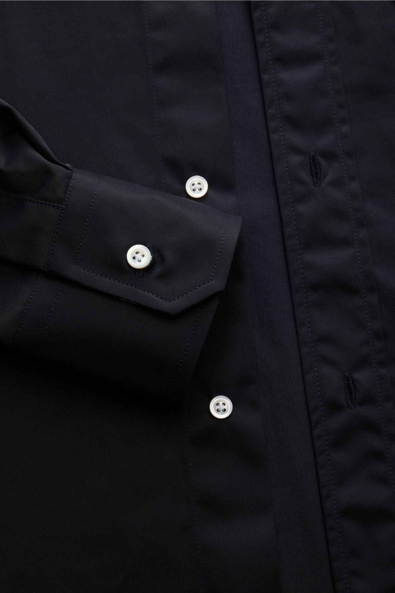 Close-up front view of the Thom Browne Overshirt - F1066 in black, showing smooth cotton-microfiber fabric, slim fit design with a buttoned cuff and white buttons on the front placket. Luxuriöses Layering-Piece: Das Overshirt von THOM BROWNE überzeugt mit