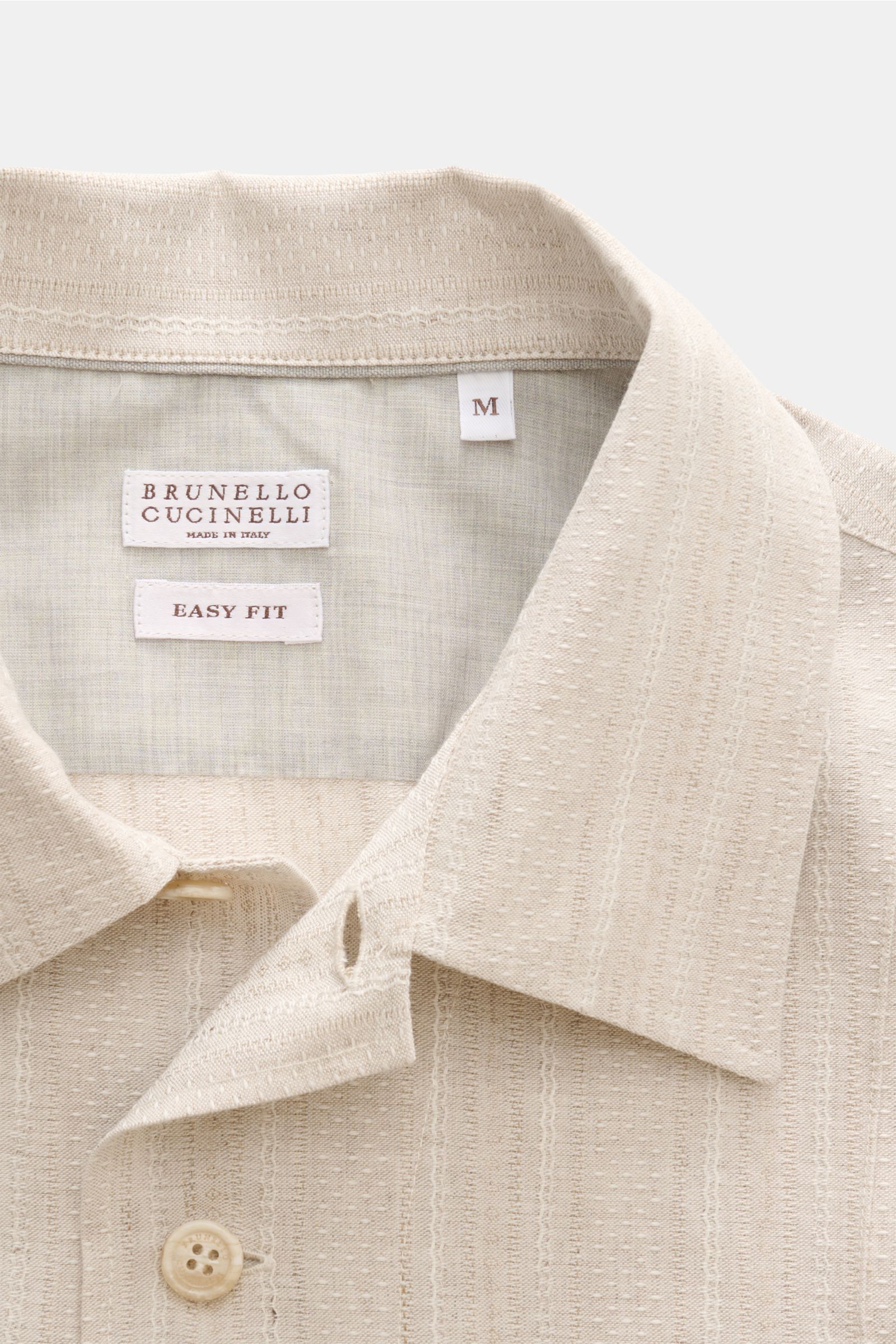 Close-up front view of the beige Brunello Cucinelli Overshirt showing collar, button, and fabric texture in slim fit easy fit design.

Description:  
Zeitloses Layering-Piece: Das Overshirt von BRUNELLO CUCINELLI ergänzt Sommerlooks mit souveräner Eleg