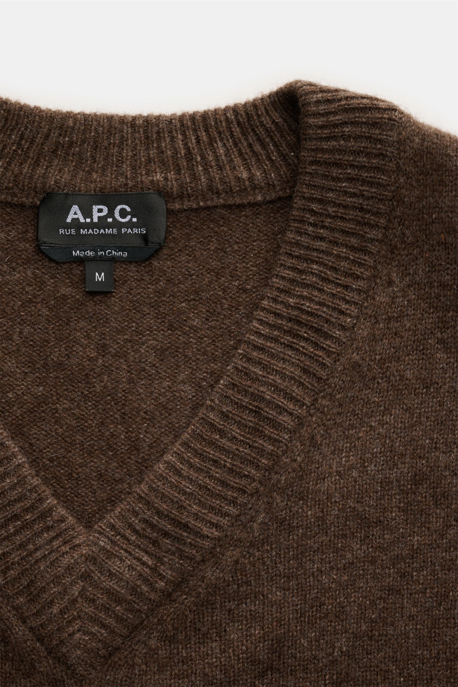 Close-up front view of the A.P.C. V-Neck Pullover 'Pull Dany' braun meliert showing ribbed V-neck collar and fabric texture with reine Yak-Wolle, weicher Griff, mittelfeines Strickbild, Slim Fit, flexible Rippbündchen.