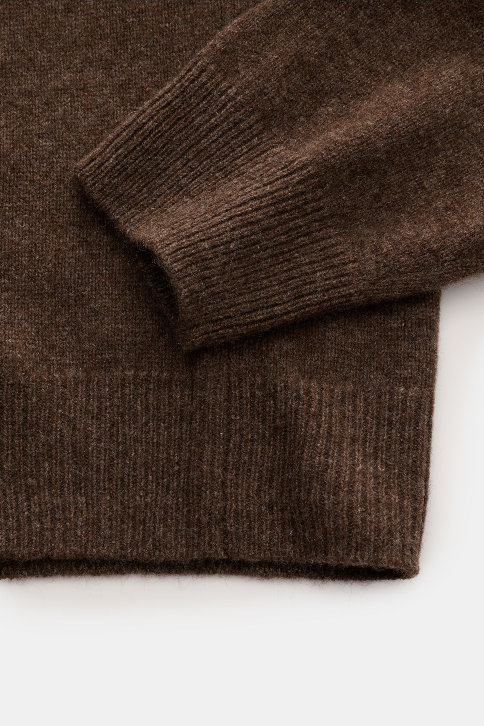 Close-up image from above of the sleeve cuff and hem of the A.P.C. V-Neck Pullover 'Pull Dany' braun meliert, showing reine Yak-Wolle, weicher Griff, mittelfeines Strickbild, Slim Fit, and flexible Rippbündchen.
