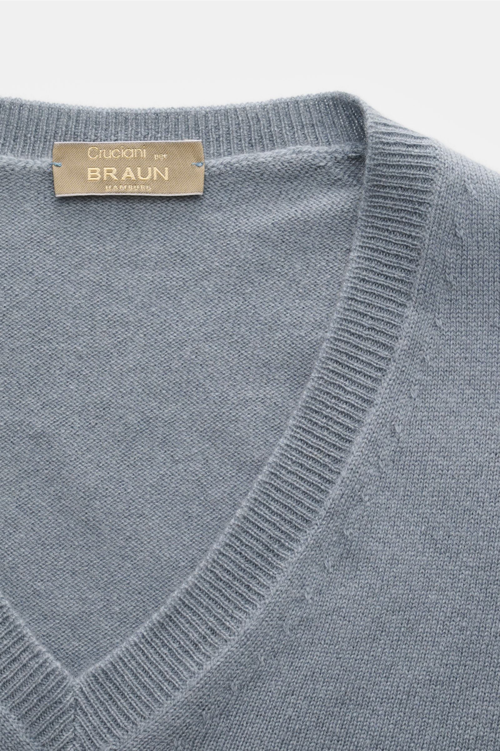 Close-up top-down view of the Cruciani Cashmere V-neck jumper smoky blue, showcasing fine knit and ribbed V-neck collar.

This V-neck jumper in pure cashmere by CRUCIANI is the epitome of understatement and style. Its smooth feel and fine knit give it 