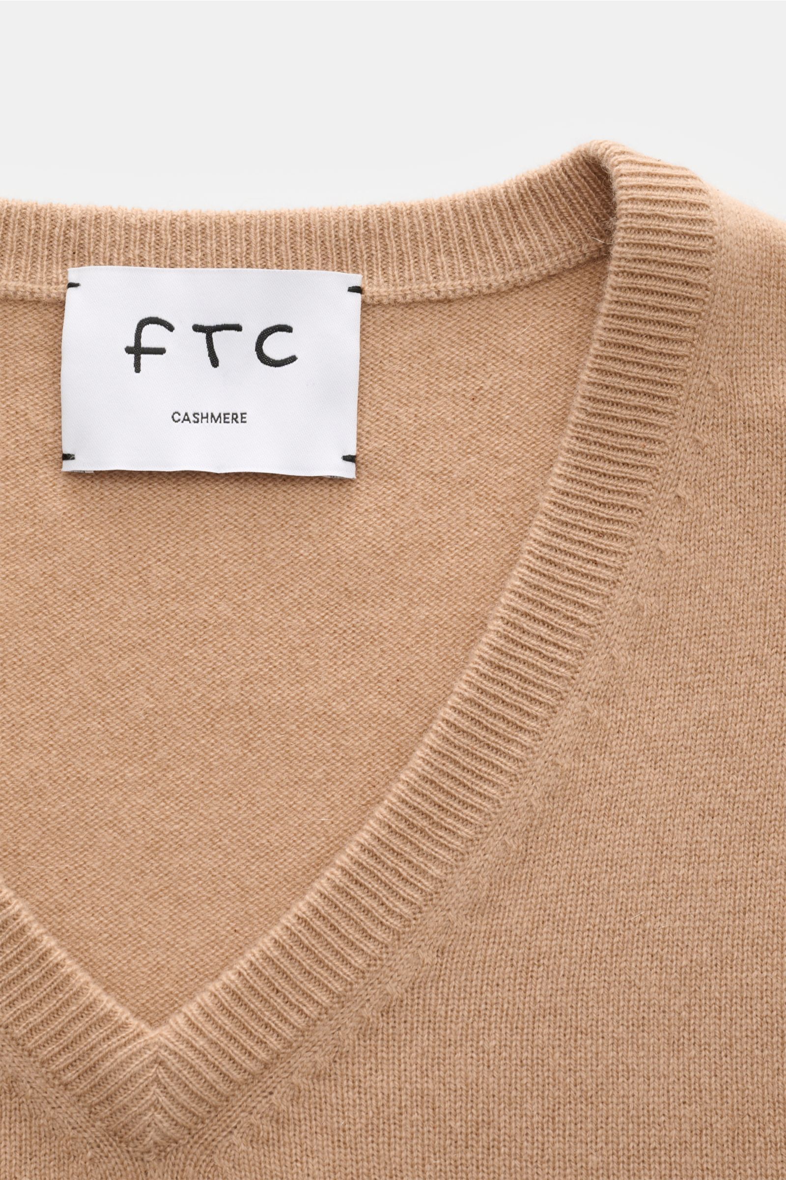 Nahaufnahme des FTC Cashmere V-Neck Pullovers beige mit V-Ausschnitt, feinem Strickbild, Slim Fit, weichem Fair-Trade-Cashmere und Rippbündchen.