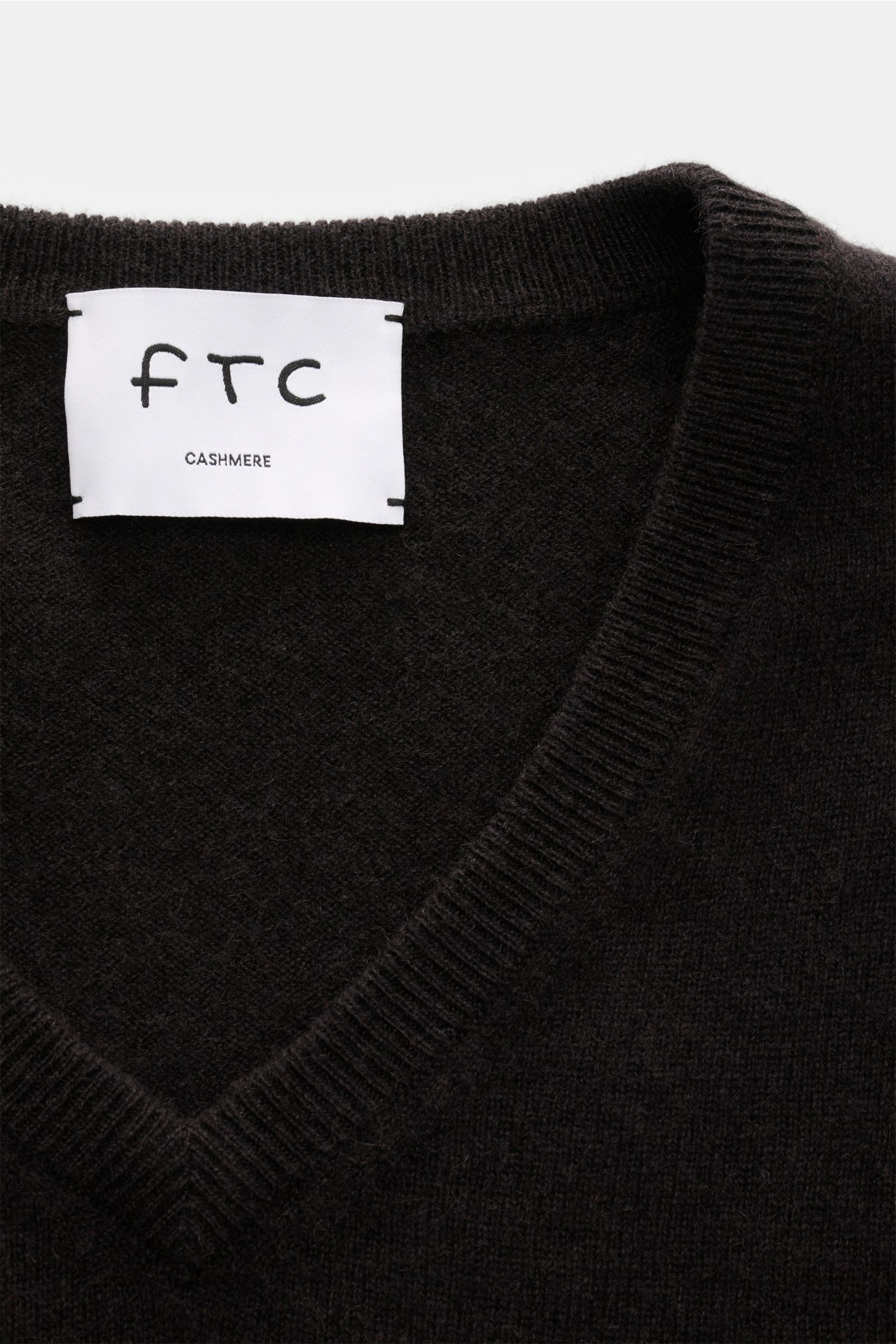 Close-up front view of the FTC Cashmere V-Neck Pullover dunkelbraun showing the V-neckline and label.  
Der Pullover mit V-Ausschnitt ist ein Klassiker der Herrenmode, der in keinem Kleiderschrank fehlen darf – aus nachhaltigem Cashmere von FTC CASHMER