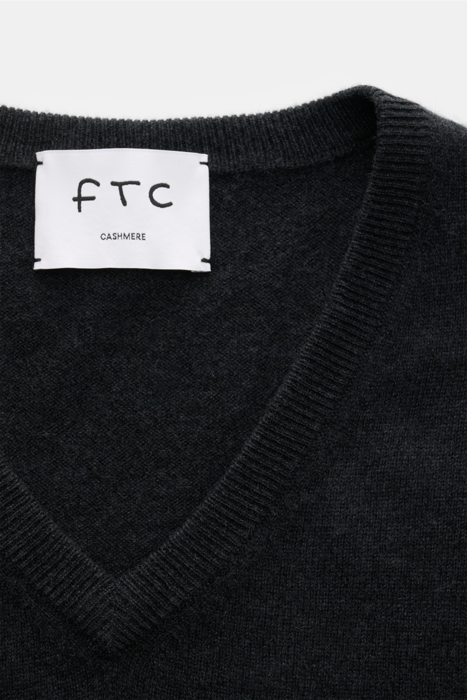 FTC Cashmere V-Neck Pullover anthrazit shown in close-up from above, highlighting the V-neck, fine knit, and label.  
Der Pullover mit V-Ausschnitt ist ein Klassiker der Herrenmode, der in keinem Kleiderschrank fehlen darf – aus nachhaltigem Cashmere v