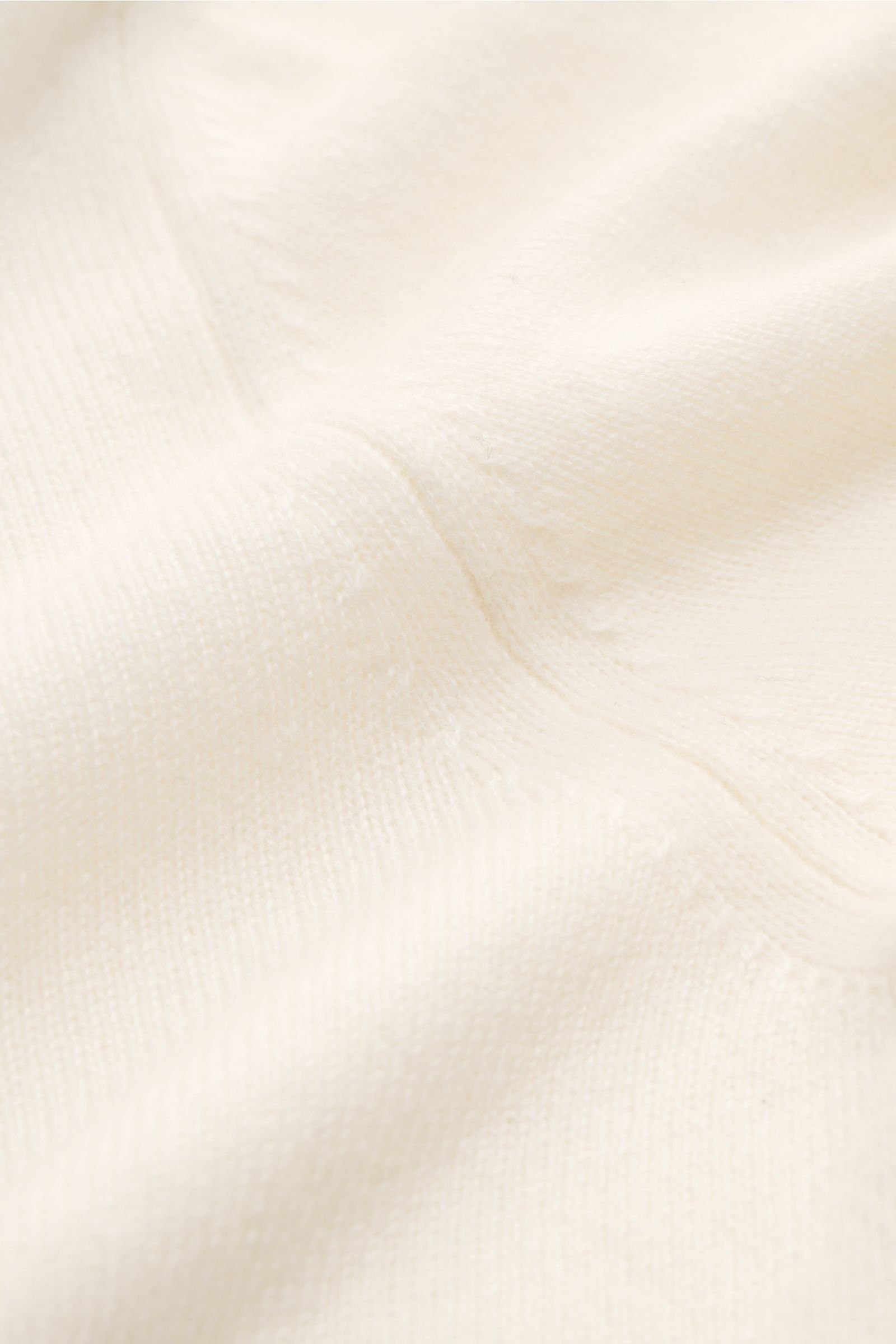 Fioroni Cashmere V-Neck Pullover creme, Nahaufnahme aus schräger Perspektive, feines Strickbild, Baby-Cashmere, Slim Fit, weiche Haptik, flexible Rippbündchen.