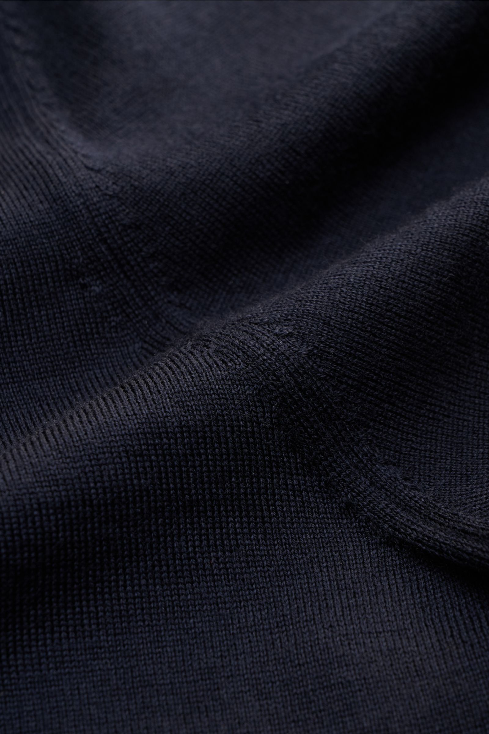 Agnona Rundhalspullover dark navy in Nahaufnahme aus schräger Perspektive, feines Strickbild, reine Wolle, Slim Fit, Rundhalsausschnitt, komfortable Rippbündchen, rückwärtiges Metalllabel.