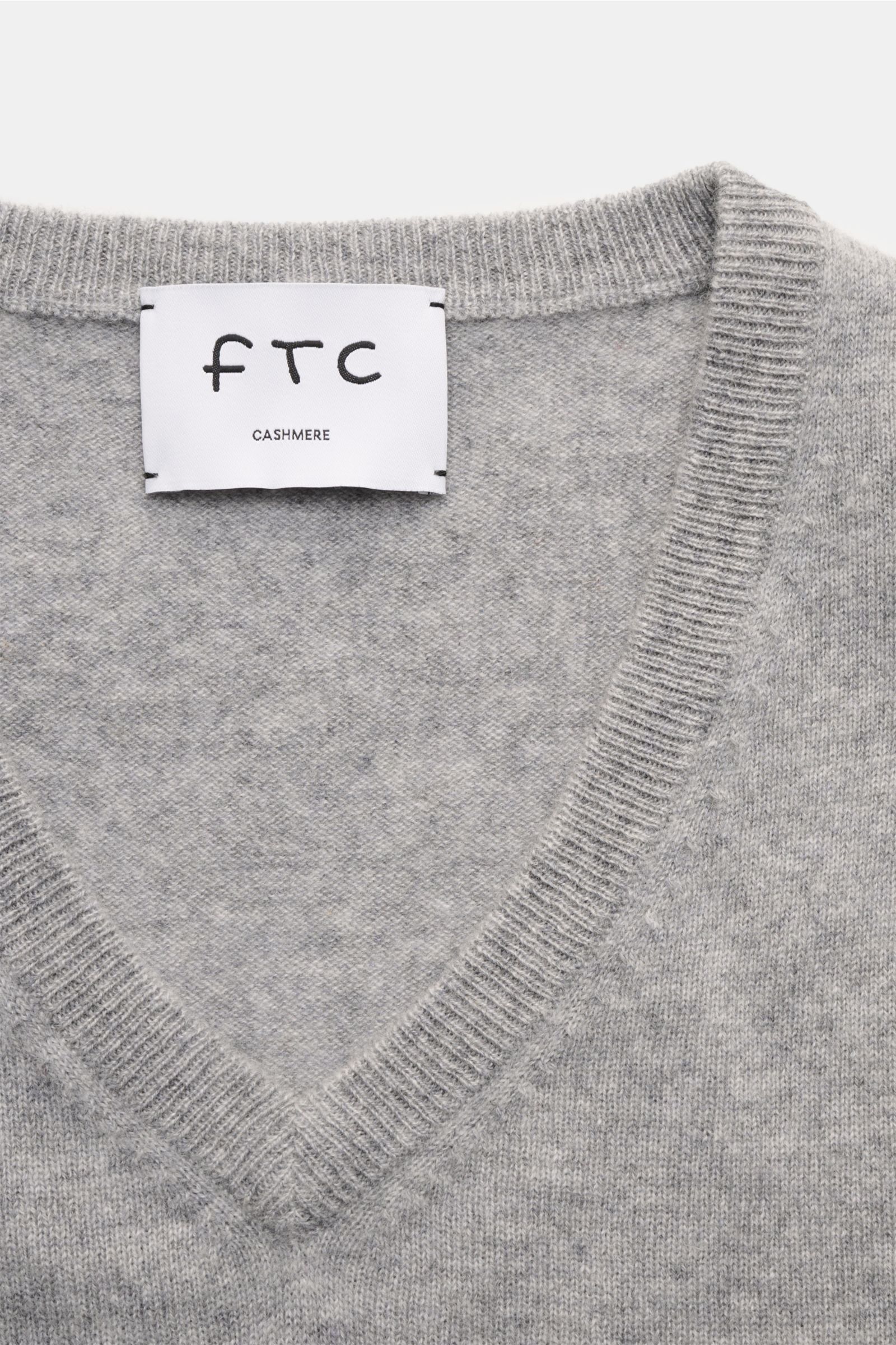 Nahaufnahme des grauen FTC Cashmere V-Neck Pullovers von oben, fein gestrickt, Slim Fit, V-Ausschnitt mit Rippbündchen, Fair-Trade-Cashmere.