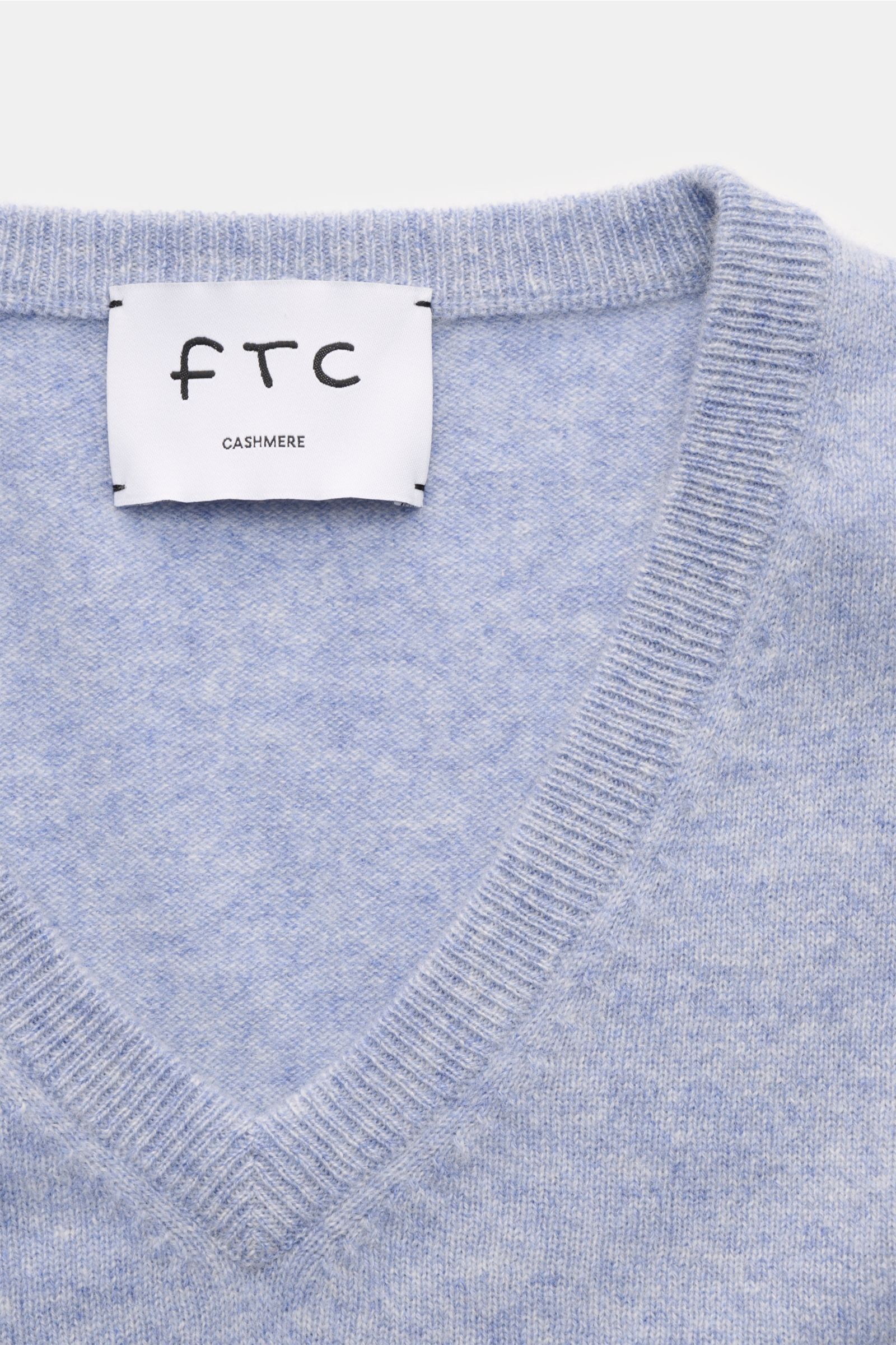 Nahaufnahme des FTC Cashmere V-Neck Pullovers hellblau meliert von oben, Slim Fit, V-Ausschnitt, reiner Fair-Trade-Cashmere, weicher Griff, feines Strickbild, Rippbündchen, nachhaltig produziert.