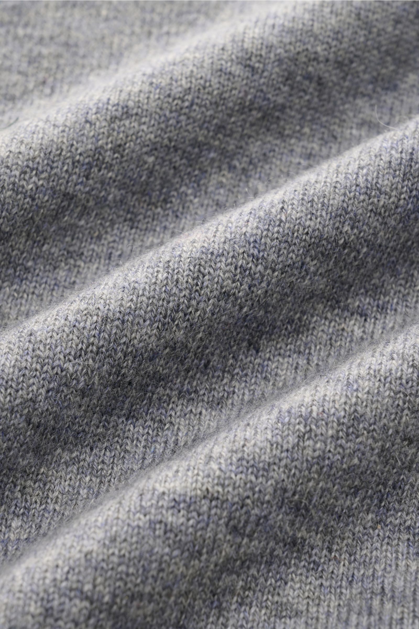 Nahaufnahme des von Braun Cashmere V-Neck Pullovers grau meliert, feines Strickbild, weicher Griff, elastische Rippbündchen sichtbar.