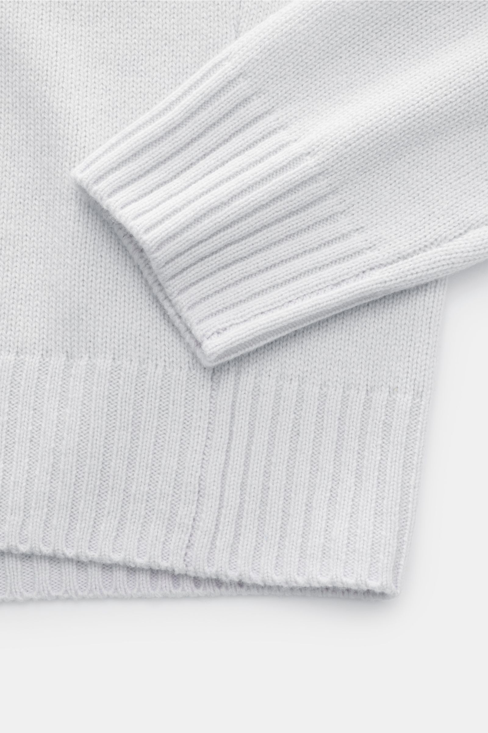 Nahaufnahme des von Braun Cashmere V-Neck Pullovers hellgrau, fotografiert von oben, zeigt mittelfeines Strickbild, elastische Rippbündchen, Slim Fit und weichen Griff aus reinem mongolischem Cashmere.