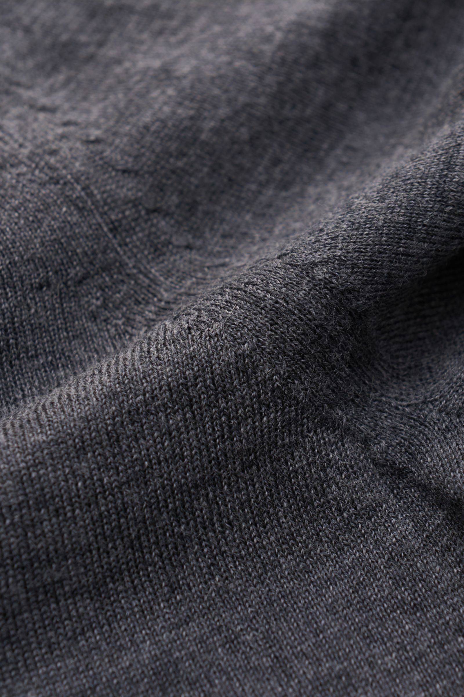 Nahaufnahme des von Braun Merino V-Neck Pullover dunkelgrau meliert mit feinem Strickbild, weichem Griff und elastischen Rippbündchen.