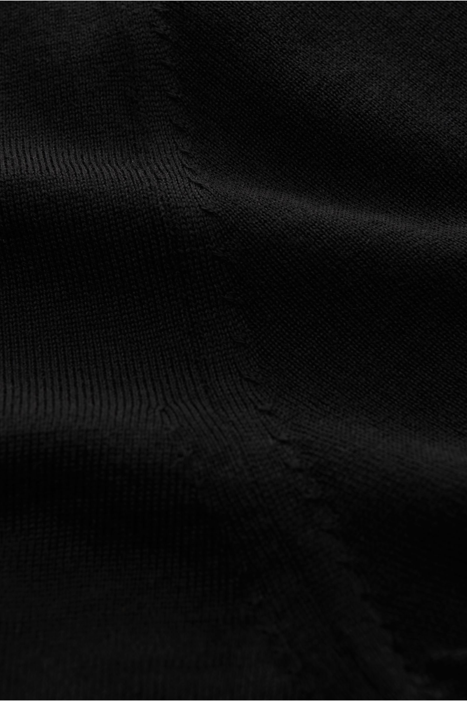 Nahaufnahme des schwarzen von Braun Merino V-Neck Pullovers aus reiner Merinowolle, feinem Strickbild, elastischen Rippbündchen und Slim Fit mit V-Ausschnitt.