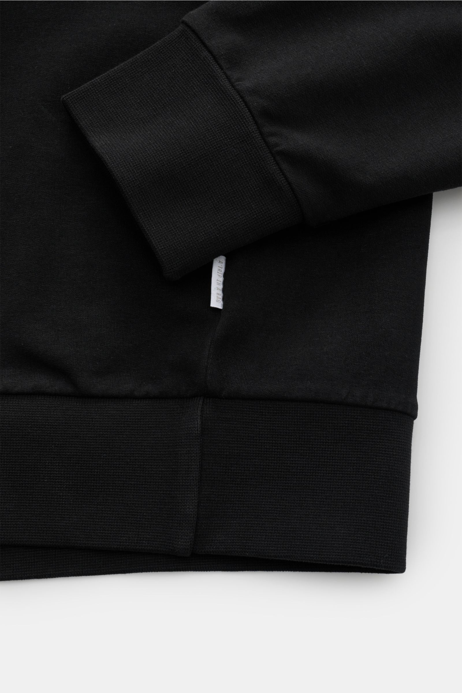 Schwarzer 04651/ A trip in a bag Kapuzenpullover 'IF Hoodie' im Detail, Nahaufnahme von Ärmel und Bund mit weichem, elastischem Jersey.