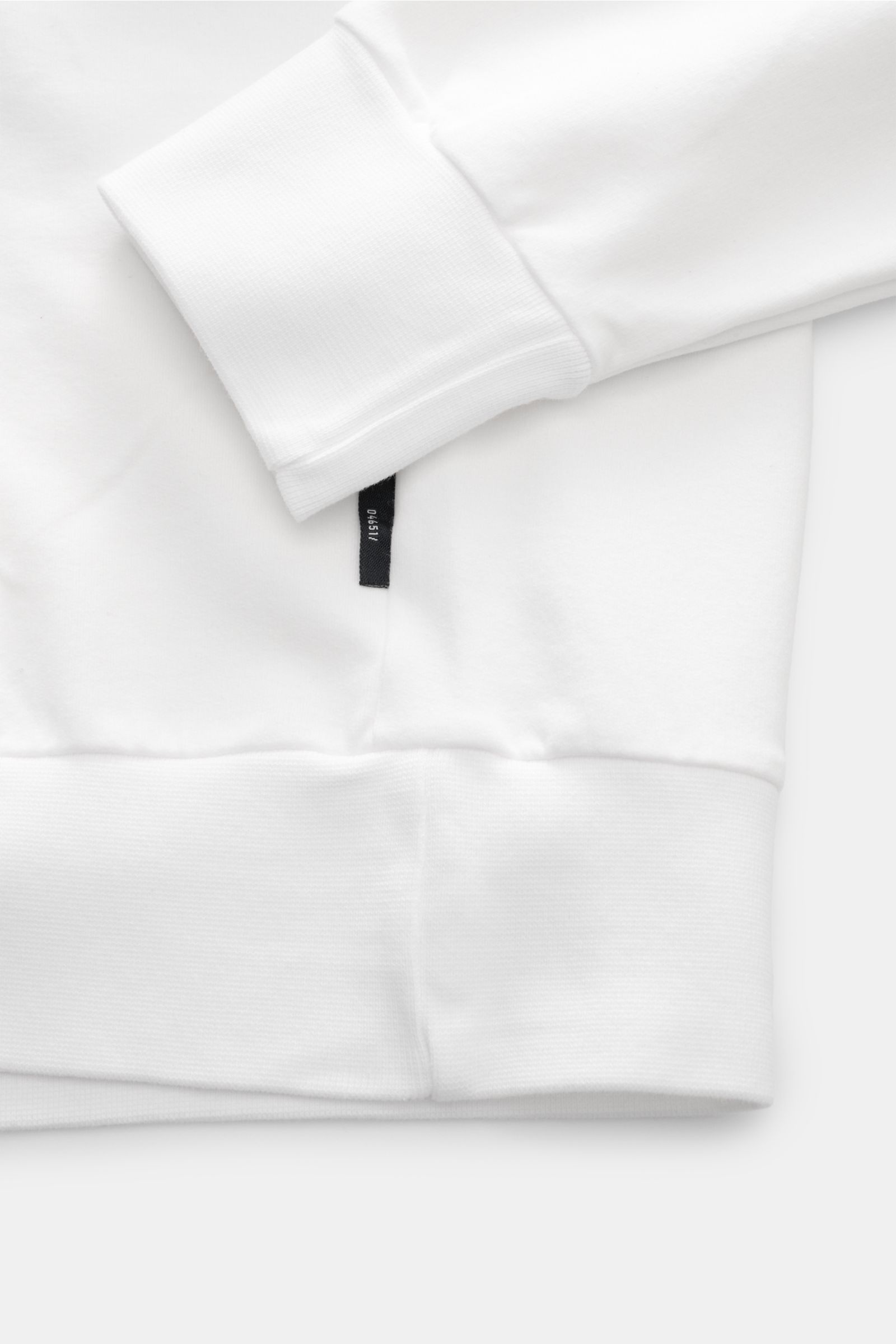 Close-up side view of the cuff, ribbed hem, and small black side label of the 04651/ A trip in a bag Kapuzenpullover 'IF Hoodie' offwhite, made of soft brushed elastic cotton jersey with comfortable ribbed cuffs and regular fit.