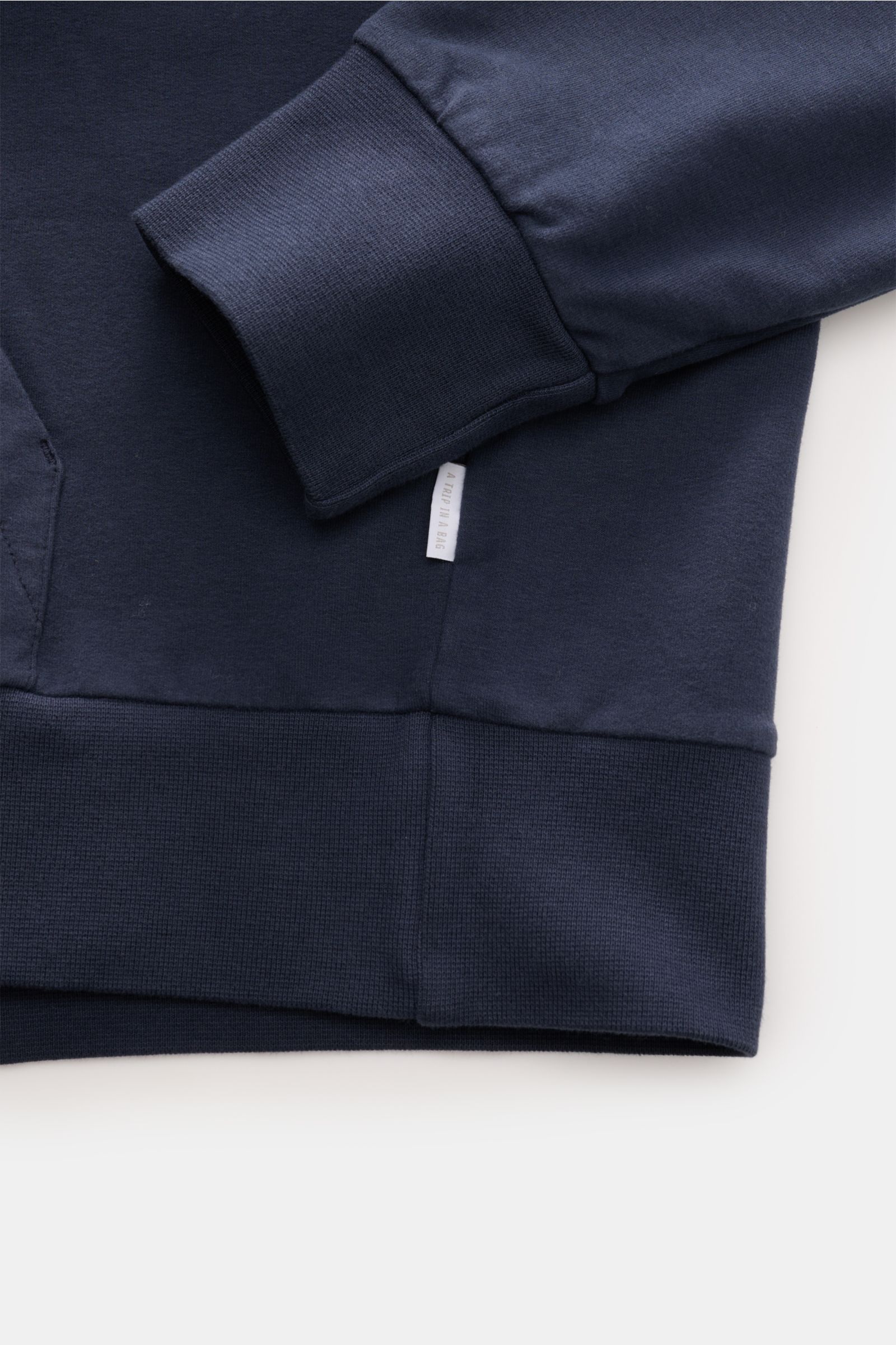 Close-up front-left view of 04651/ A trip in a bag Hooded jumper 'IF Hoodie' dark blue showing ribbed bands, soft stretchy cotton, and side seam woven label.