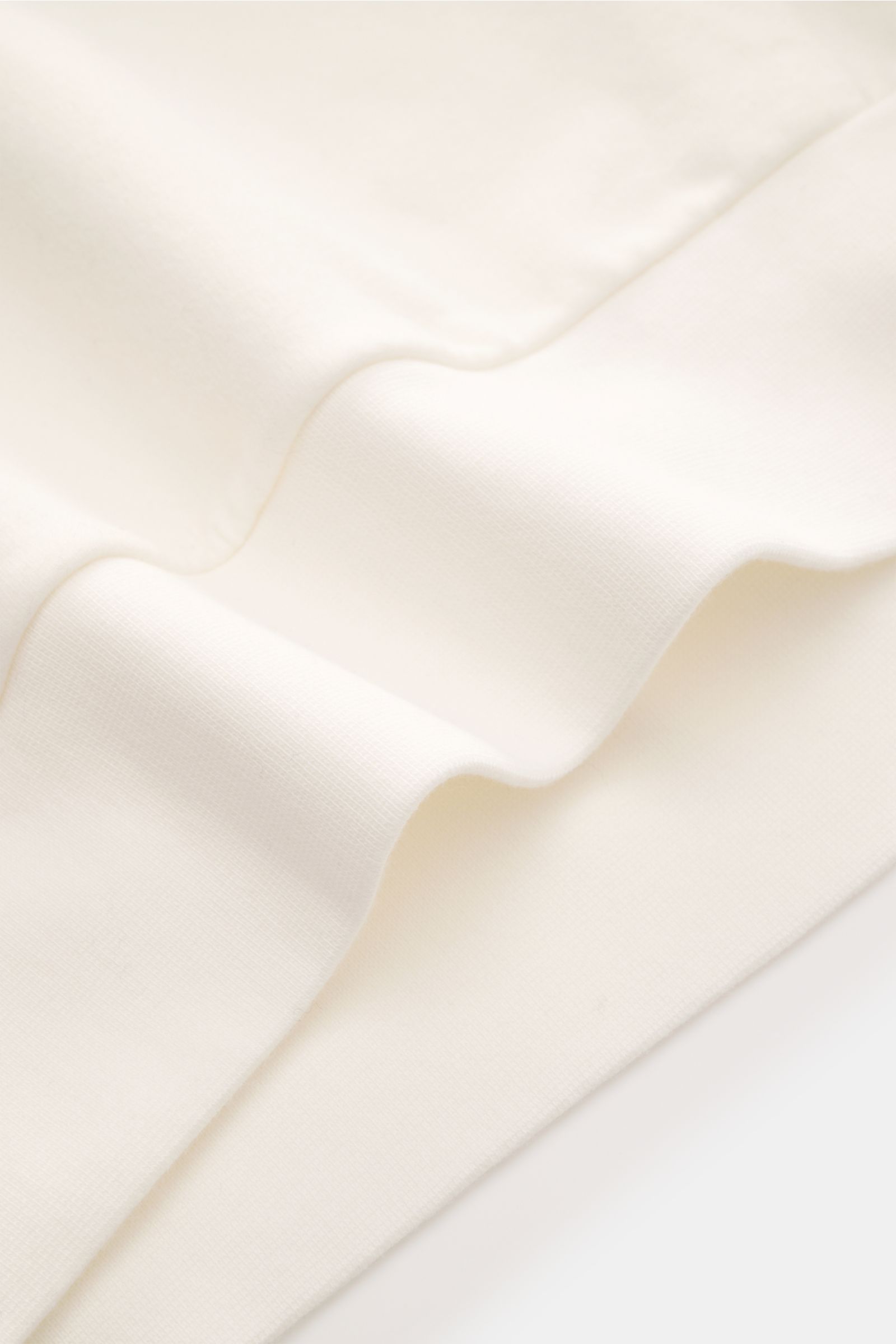 Close-up front view of the soft, offwhite fabric of the 04651/ A trip in a bag Kapuzenpullover 'IF Hoodie' showing brushed jersey texture, ribbed cuffs, and elastic cotton for comfort.