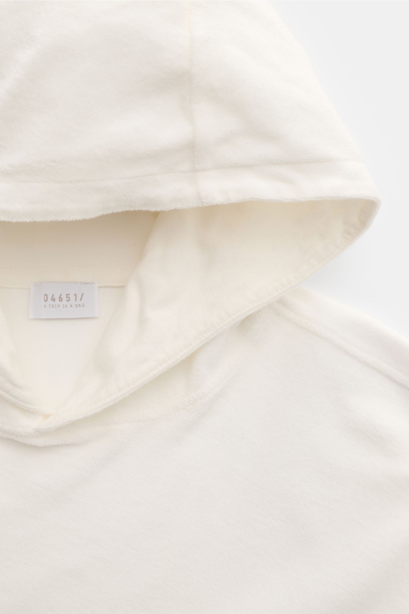 Close-up front view of the cream 04651/ A trip in a bag Terry hooded jumper 'Terry' showing the hood and label, made of pure cotton terrycloth.

Description:
Comfort and coolness with summery nonchalance: The hooded jumper 'Terry' by 04651/ A TRIP IN A