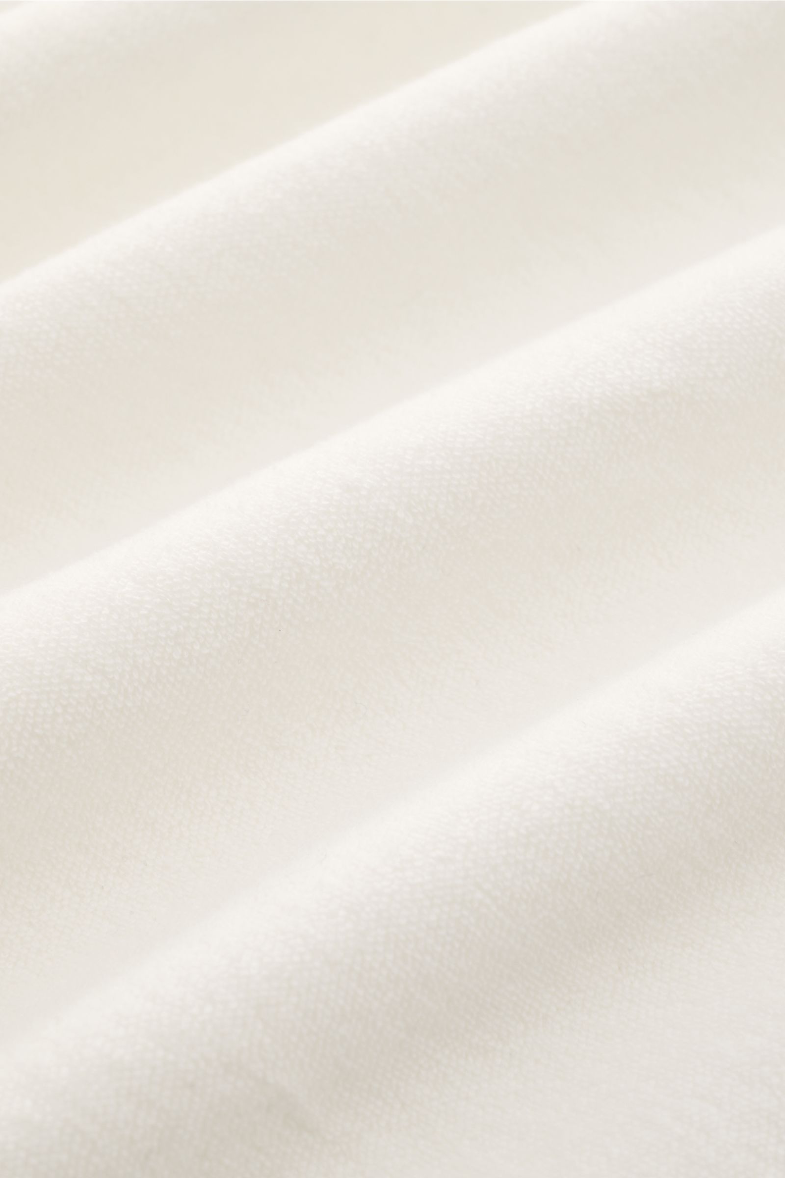 Close-up fabric texture of 04651/ A trip in a bag Terry hooded jumper 'Terry' cream, showing soft, pure cotton terrycloth from a top-down perspective.

Comfort and coolness with summery nonchalance: The hooded jumper 'Terry' by 04651/ A TRIP IN A BAG m