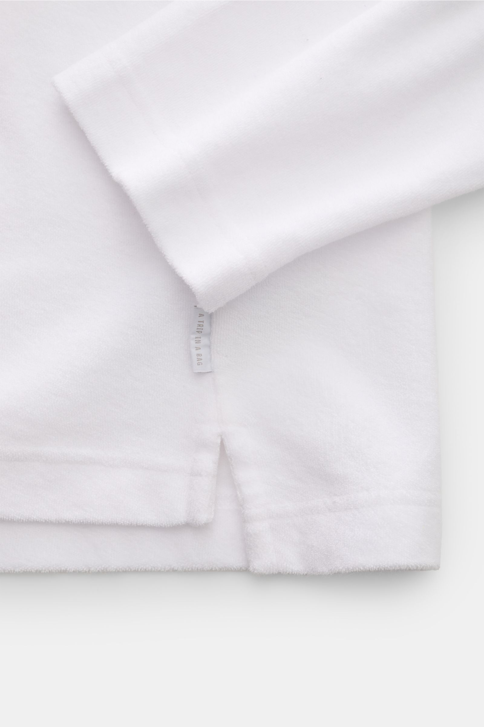 Close-up rear view of the hem and sleeve detail of 04651/ A trip in a bag Terry hooded jumper 'Terry' white in soft pure cotton terrycloth.

Comfort and coolness with summery nonchalance: The hooded jumper 'Terry' by 04651/ A TRIP IN A BAG made of pure