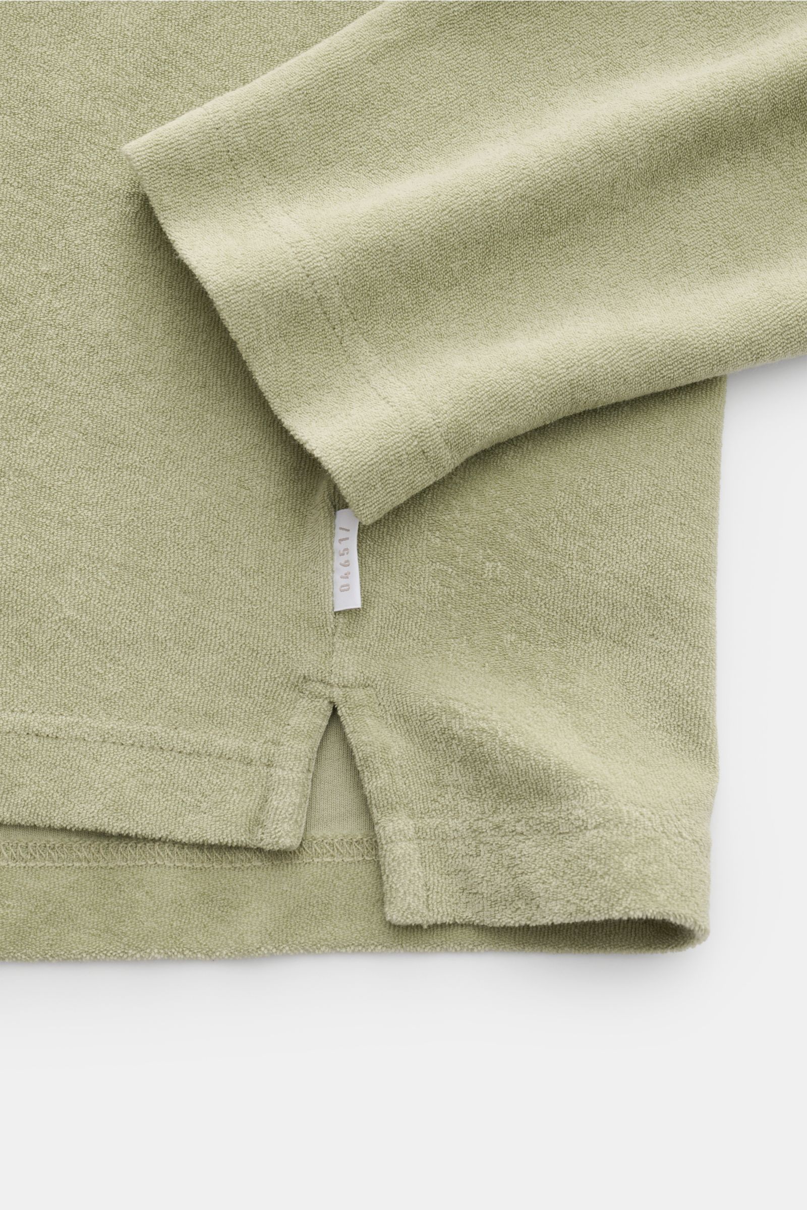 Close-up, top-down view of the hem and sleeve of the 04651/ A trip in a bag Terry hooded jumper 'Terry' sage made of soft pure cotton terrycloth with a regular fit, practical hood, and a small woven label in the side seam. Comfort and coolness with summer