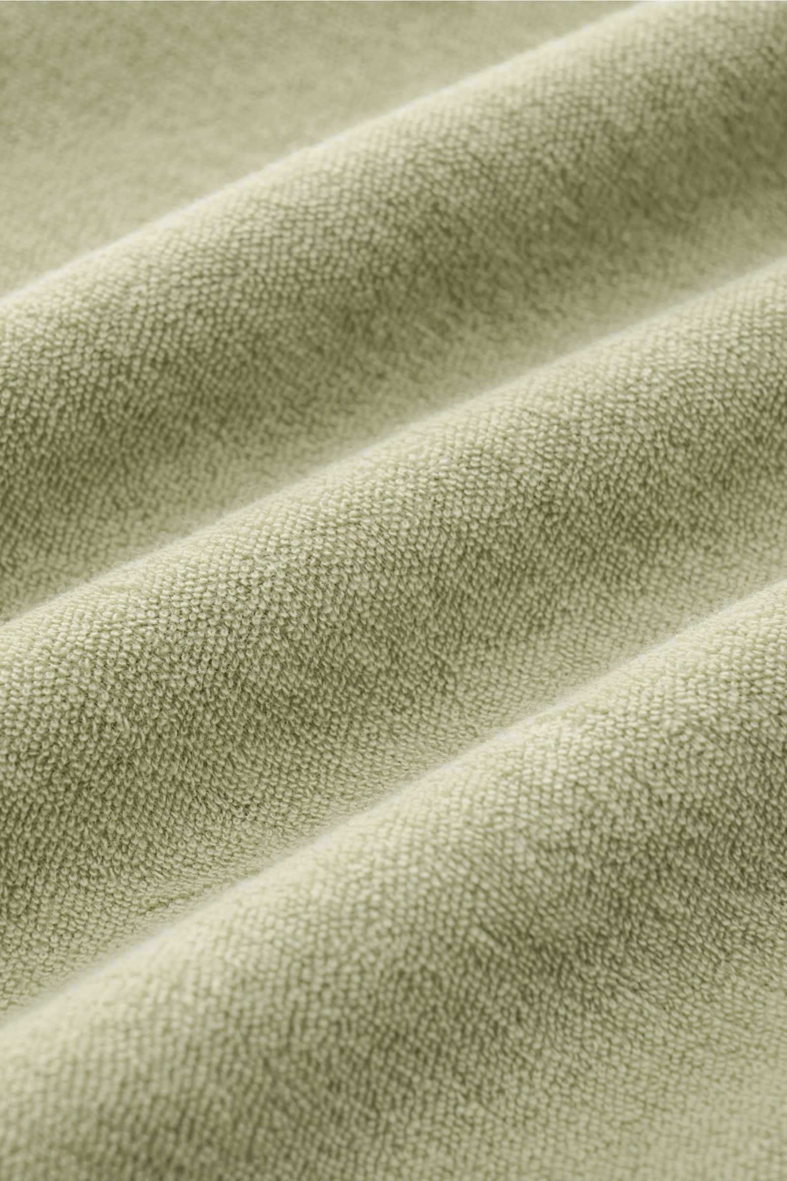 Close-up front view of the soft, sage terrycloth fabric of the 04651/ A trip in a bag Terry hooded jumper 'Terry' sage.

Description: Comfort and coolness with summery nonchalance: The hooded jumper 'Terry' by 04651/ A TRIP IN A BAG made of pure cotton