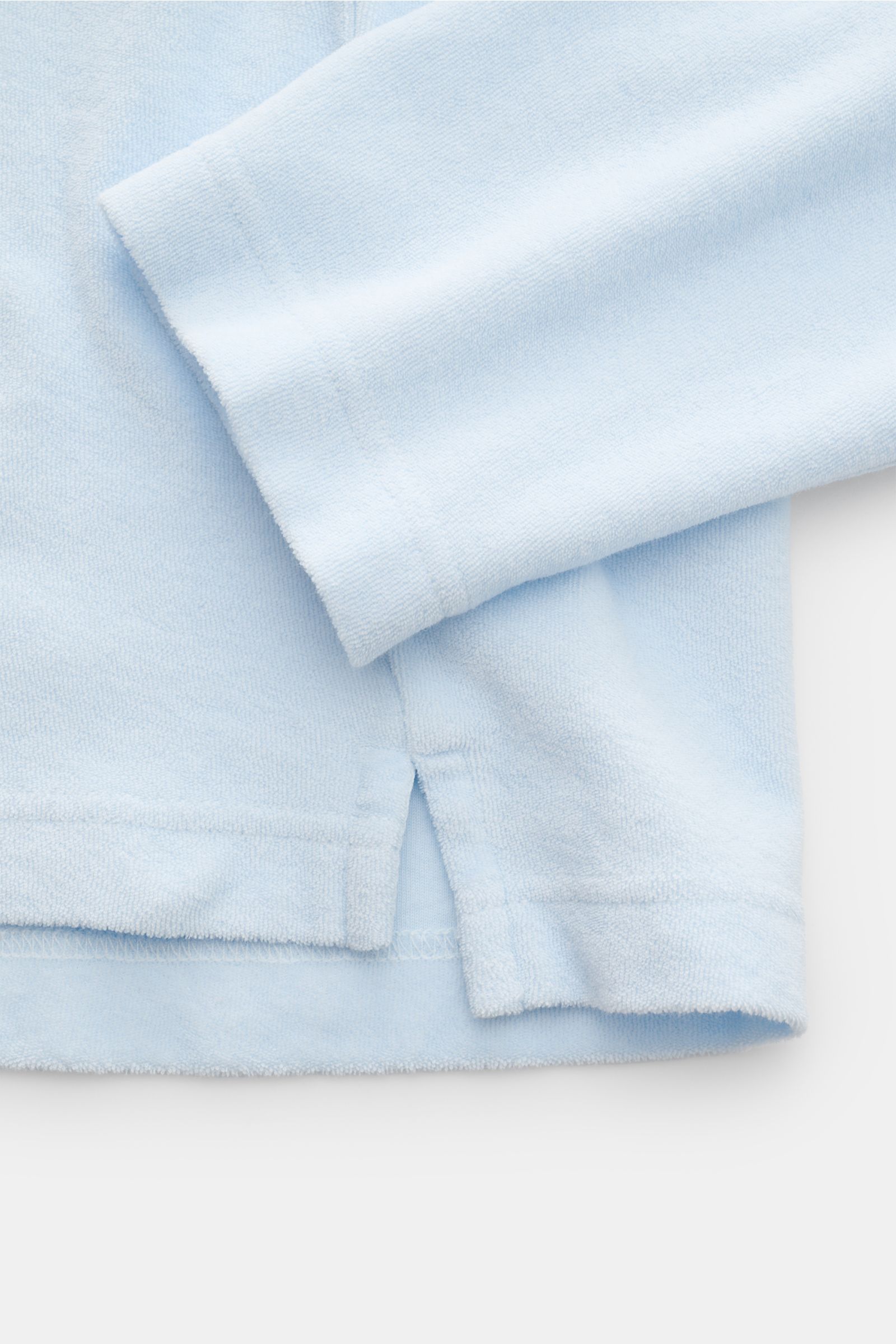 Close-up front view of the pastel blue 04651/ A trip in a bag Terry hooded jumper 'Terry' showing soft cotton terrycloth fabric, cuff, and side seam with small woven label. Comfort and coolness with summery nonchalance: The hooded jumper 'Terry' by 04651/