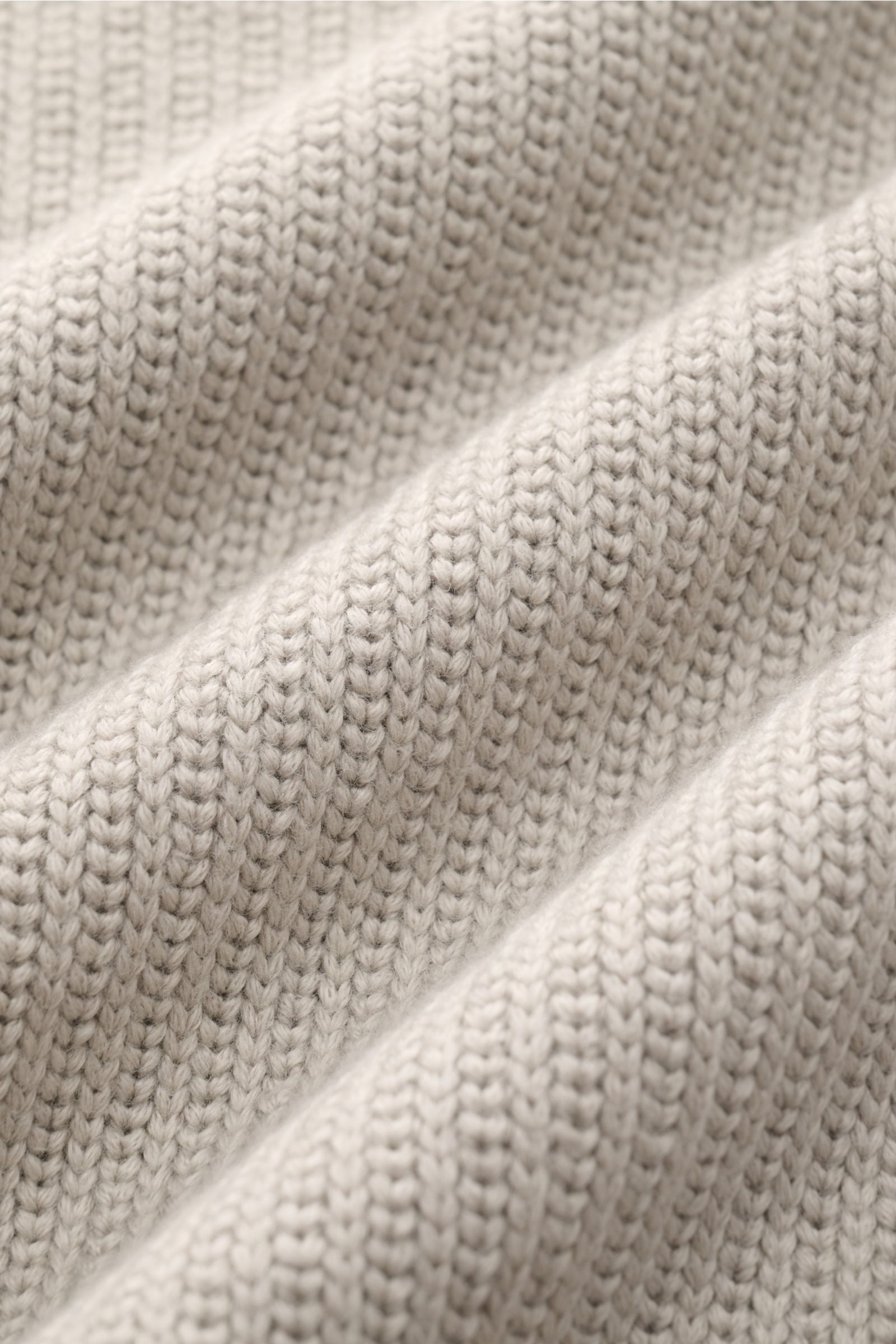 Stone Island Pullover hellgrau in Nahaufnahme, dichte Baumwoll-Microfaser-Strickstruktur, Slim Fit mit Stehkragen und Kompass-Badge am Ärmel.