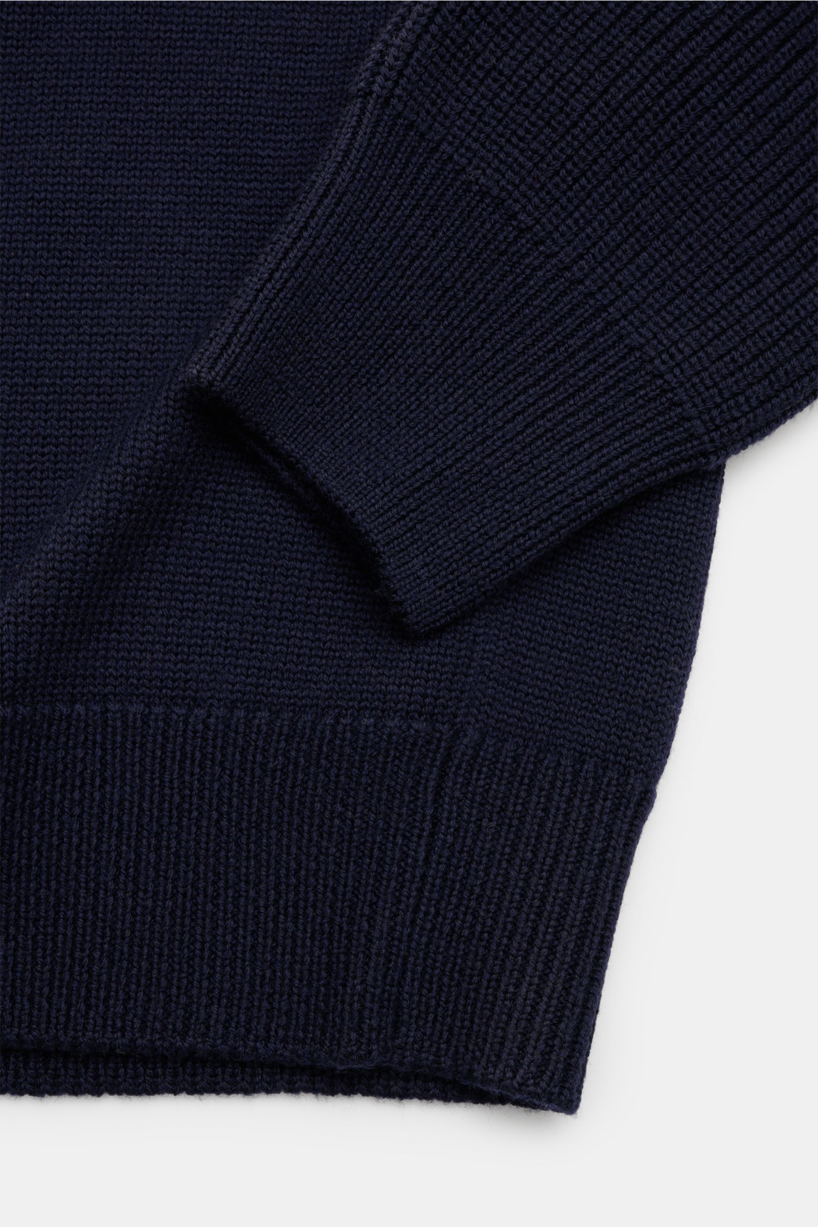 Close-up image of the Belstaff Troyer 'Aspect Quarter Zip' navy, showing the sleeve and bottom hem from a top-down angle, highlighting the pure wool, soft feel, medium-fine knit, regular fit, quarter-zip Troyer collar, Belstaff label on the upper arm, and