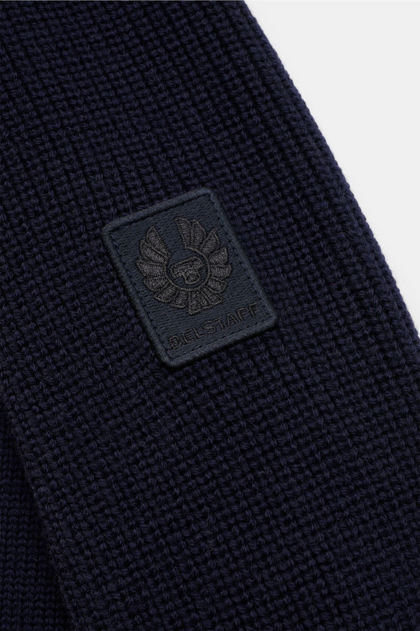 Close-up view of the navy Belstaff Troyer 'Aspect Quarter Zip' showing the textured mid-fine knit wool fabric and a dark Belstaff label on the upper arm. Zeitlos-elegant durch die kalte Jahreszeit: Der Troyer von BELSTAFF wurde aus extrafeiner Wolle gefer