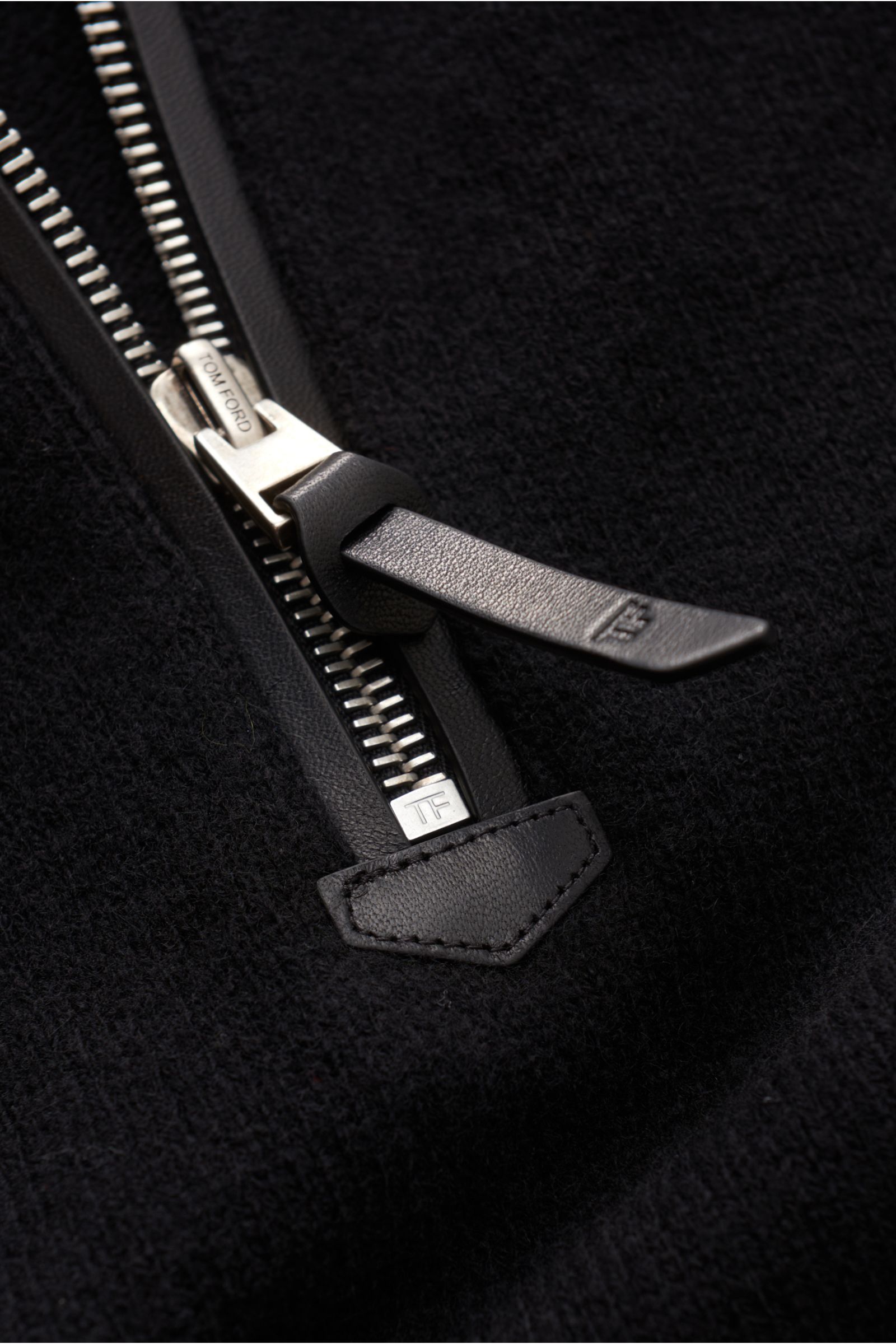 Close-up front angle of the Tom Ford Troyer schwarz zipper detail on black knit fabric, mix aus Wolle und Cashmere, sehr weicher Griff, feines Strickbild, Regular Fit, Troyer-Kragen mit Zipper, Raglanärmel, flexible Rippbündchen.