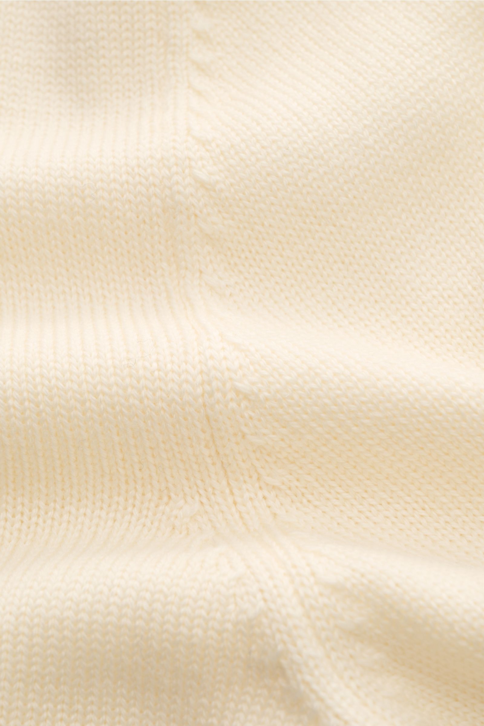 Close-up of the Gran Sasso Rollkragenpullover creme fabric, showing its soft, fine knit texture and creamy color from a top-down perspective. Ein komfortables Basic für vielseitige Looks: Der edle BRAUN HAMBURG Rollkragenpullover aus reiner Schurwolle 