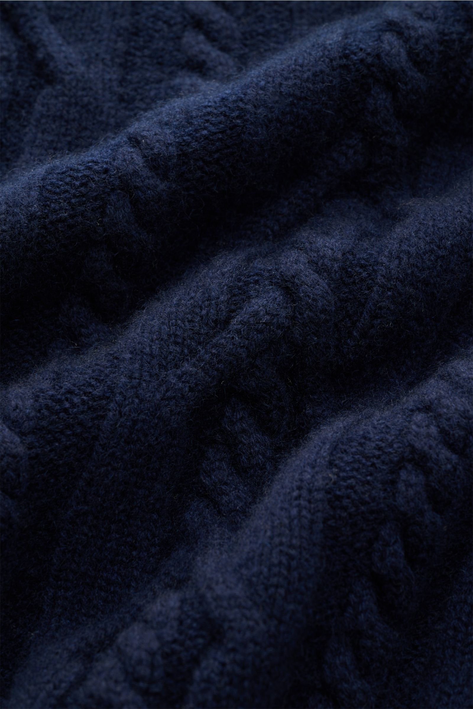 Close-up front view of the Fedeli Cashmere Rollkragenpullover 'Moena' navy, showcasing its soft, luxurious cable-knit pattern. The epitome of a winter sweater, this pure cashmere slim fit features a high, snug turtleneck and comfortable ribbed cuffs. D